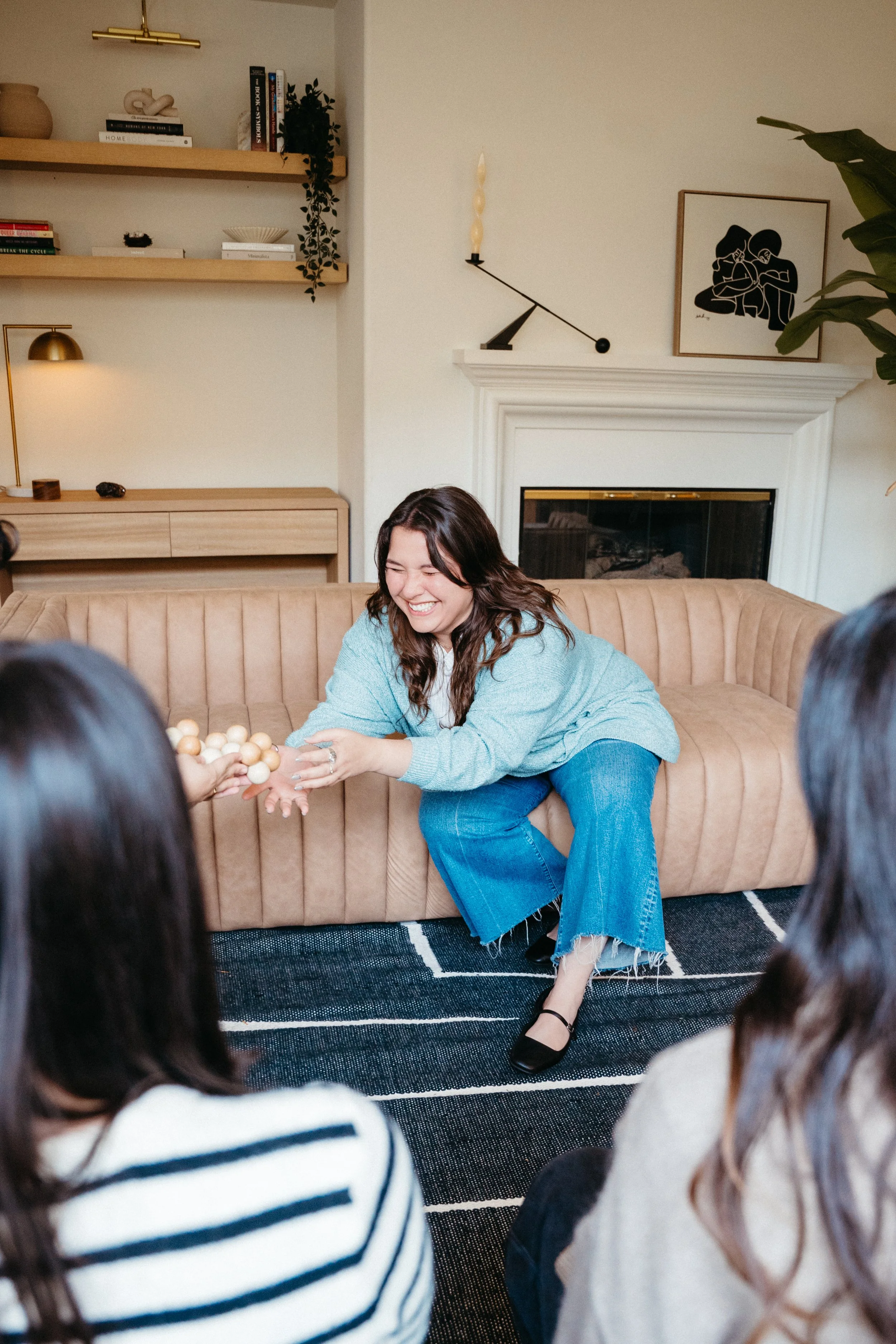 Photo of a Nido IFT therapist sitting across from two clients on a couch and whole-body laughing