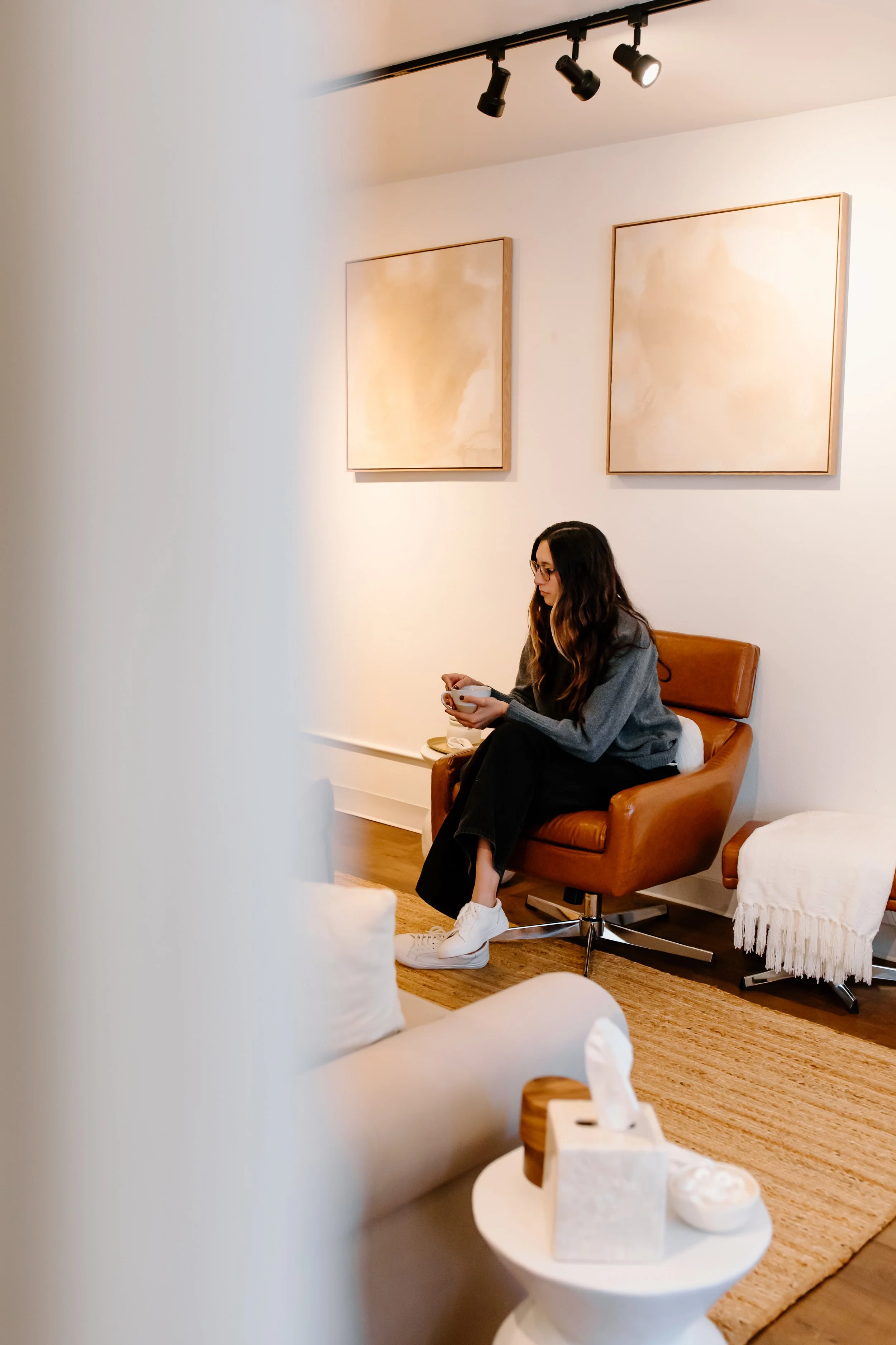 Photo of Nido IFT founder Sarah Finch sitting in an armchair in a hallway holding a cup of tea