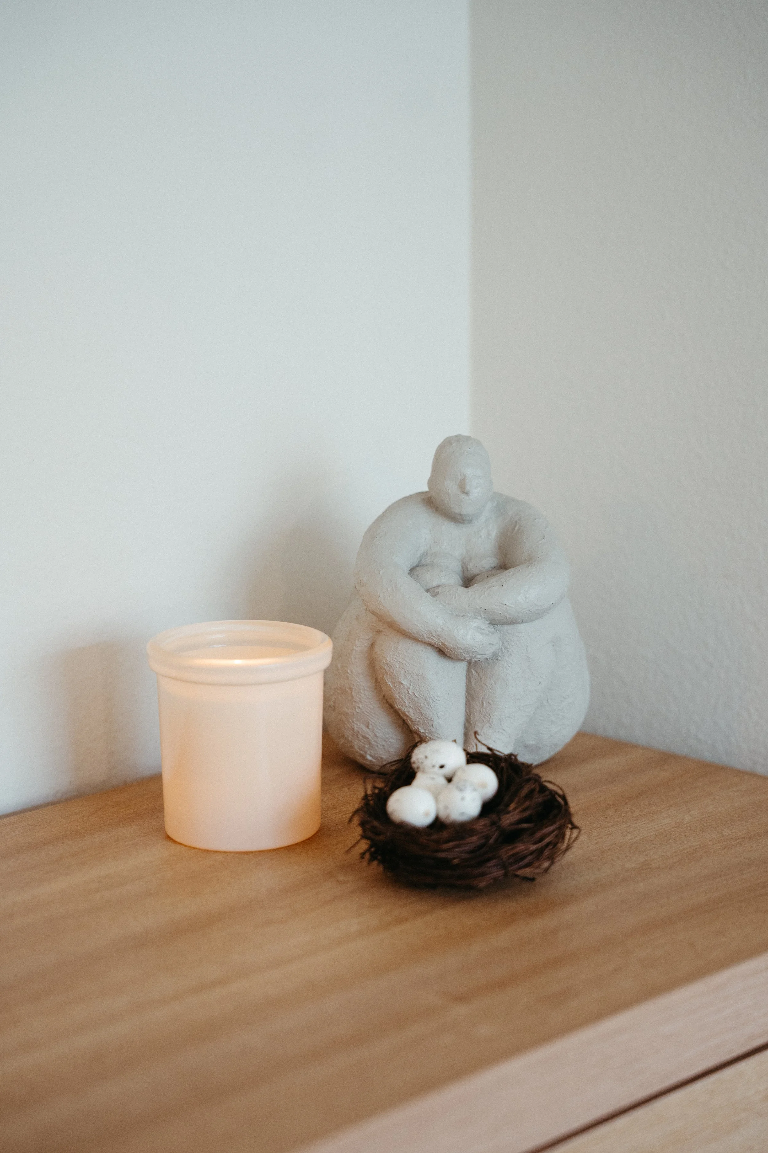 Photo of a corner of the Nido office with a candle, small nest with spotted eggs, and statue of a person holding their legs