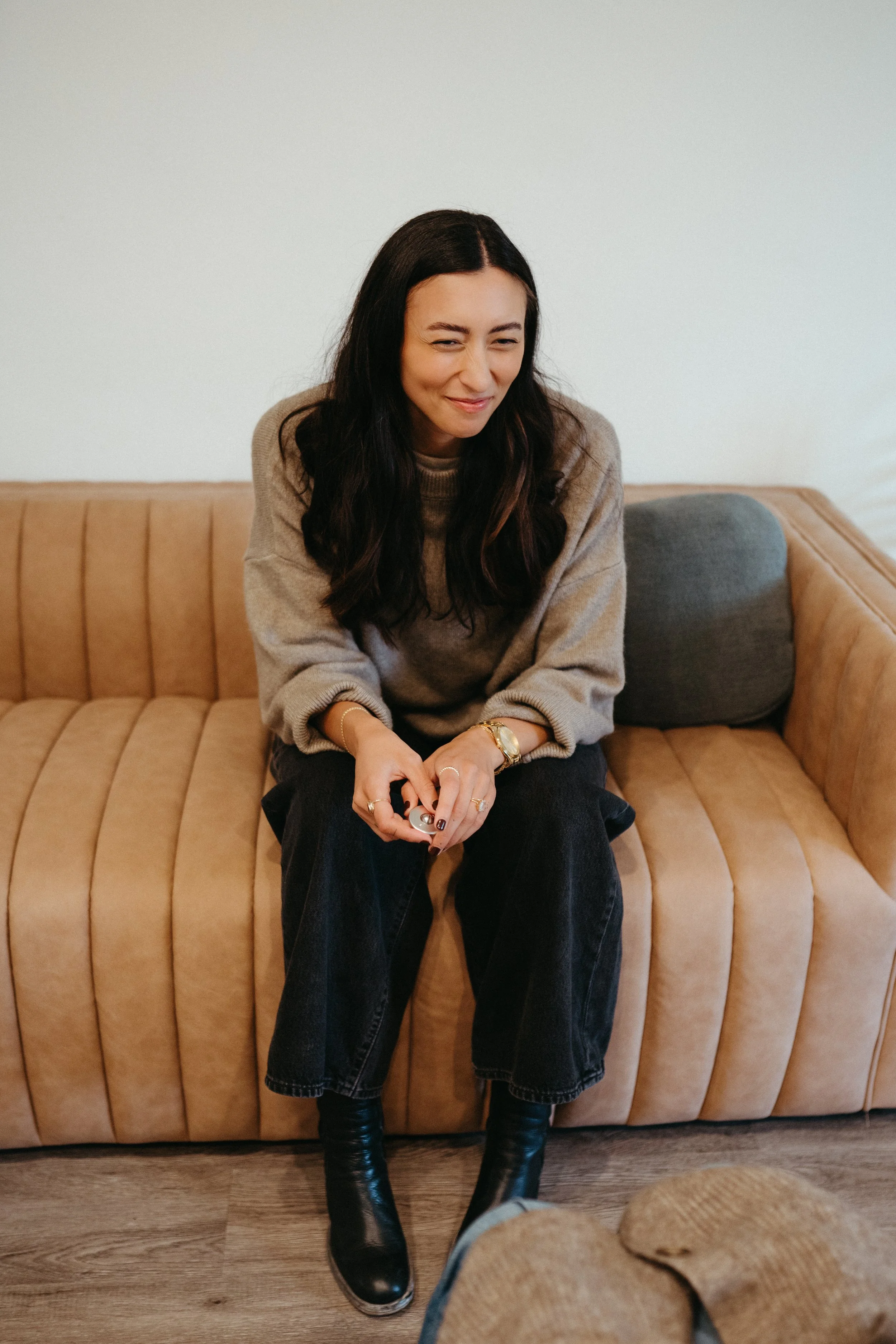 Photo of Nido IFT founder Sarah sitting on a couch and smiling with her eyes while looking at someone out of frame