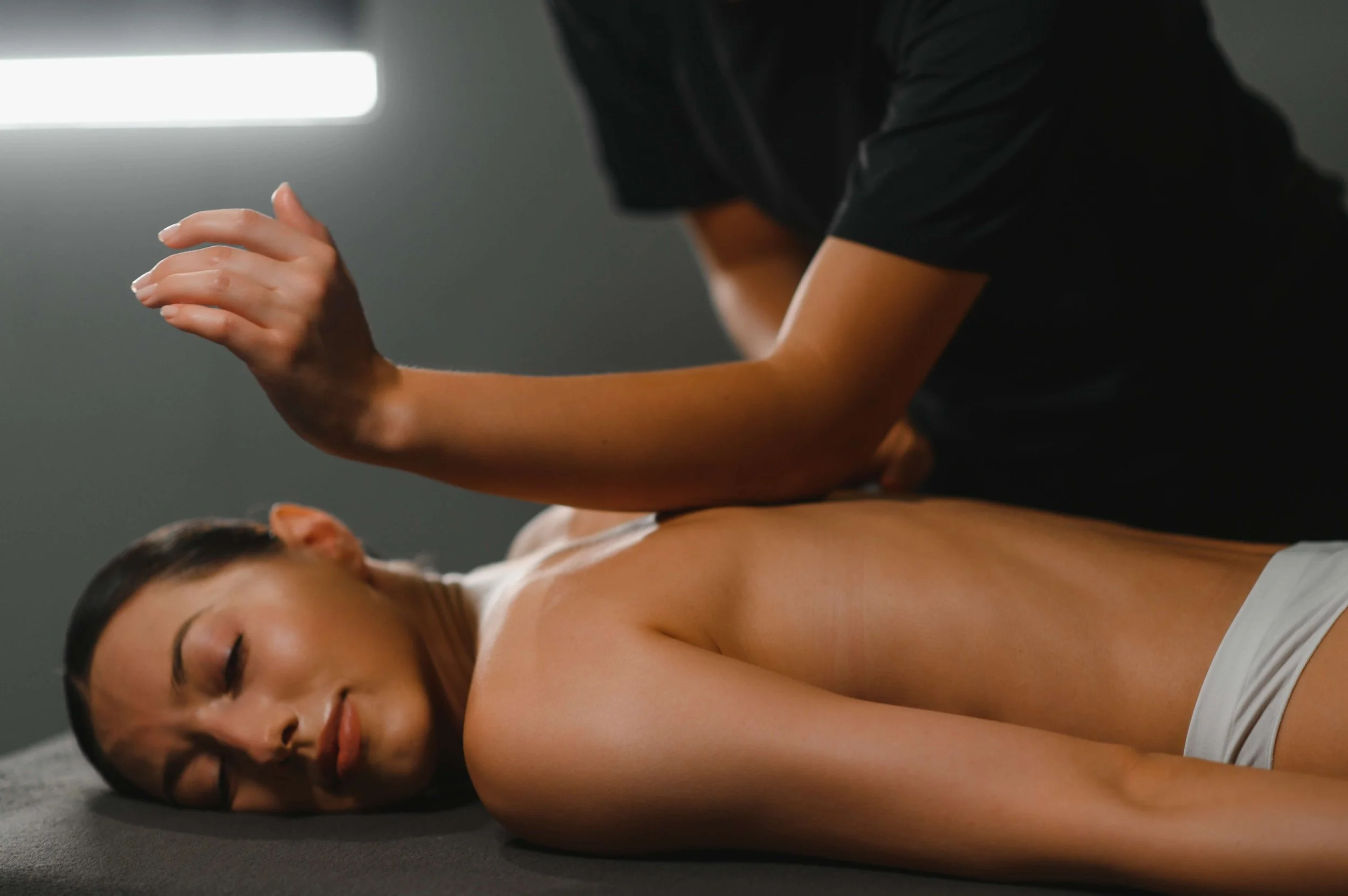 A woman lying face down on a massage table, receiving a massage from a therapist.