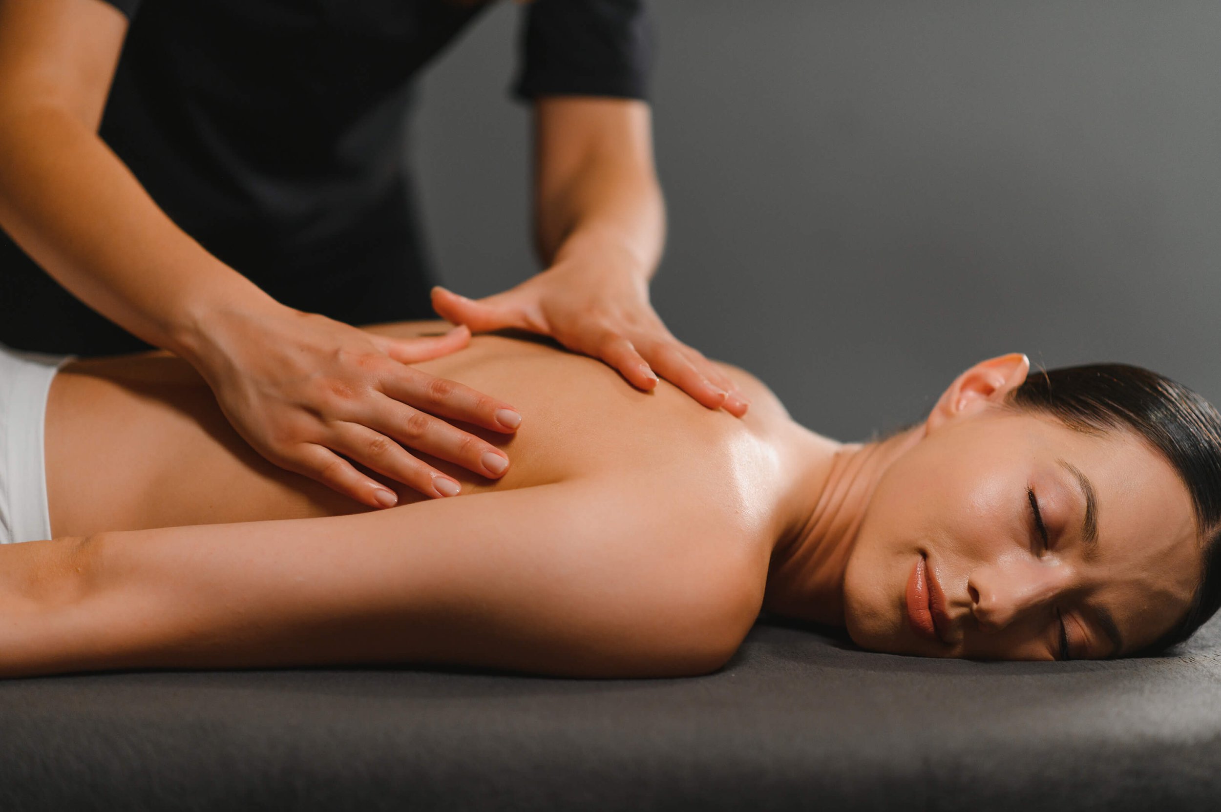 Woman lying face down while receiving a back massage from massage therapist.