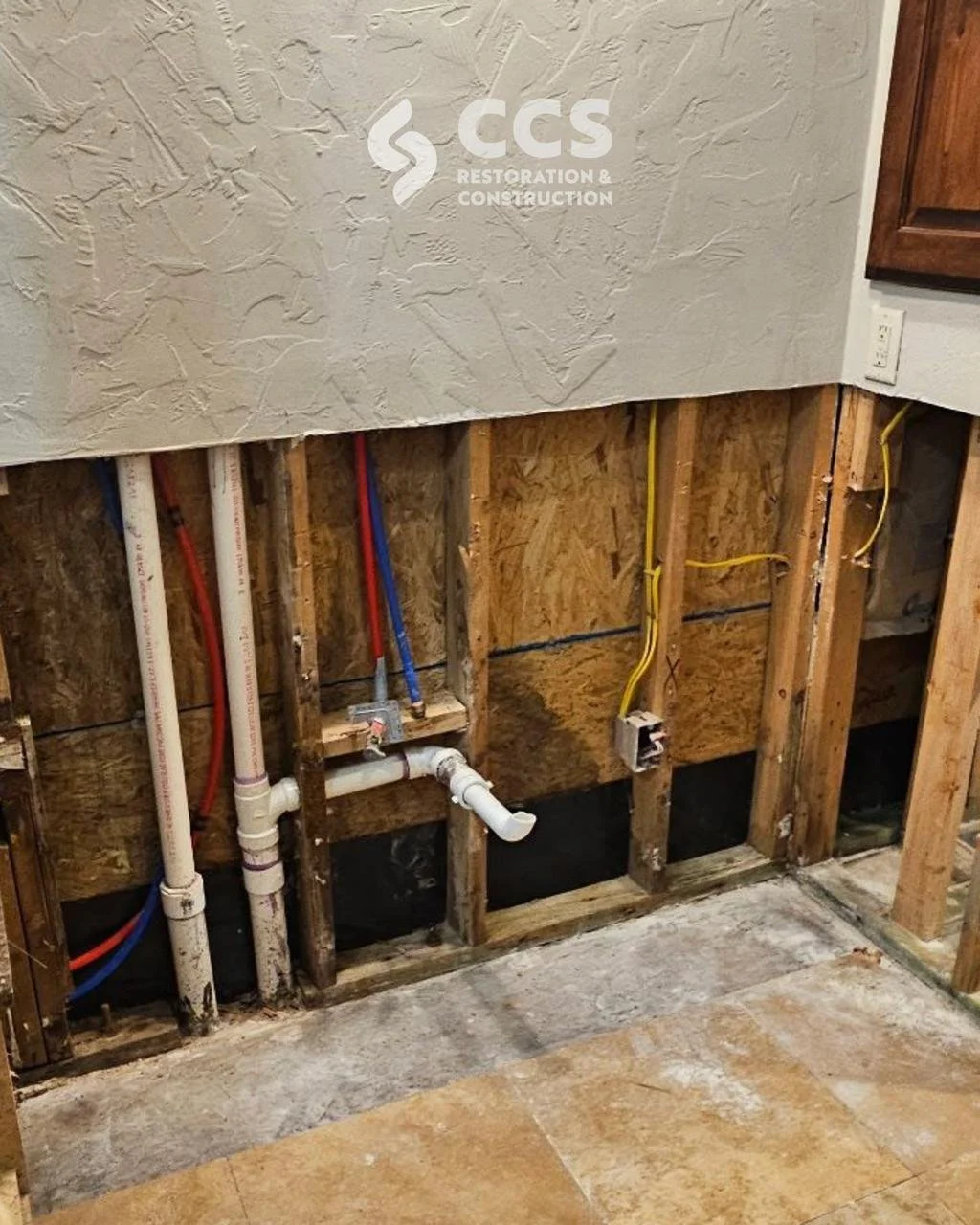 Interior wall with exposed plumbing and electrical wiring during renovation process.