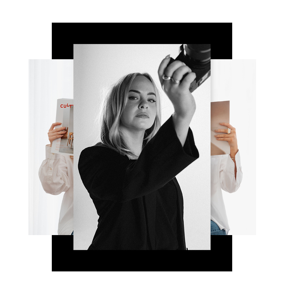 Black and white portrait of a woman holding a camera, looking directly at the lens, with two partially visible people holding books behind her.