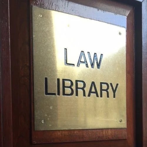 A brass plaque with the words "LAW LIBRARY" mounted on a wooden wall.