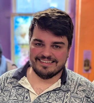 A man with short, wavy hair, smiling.