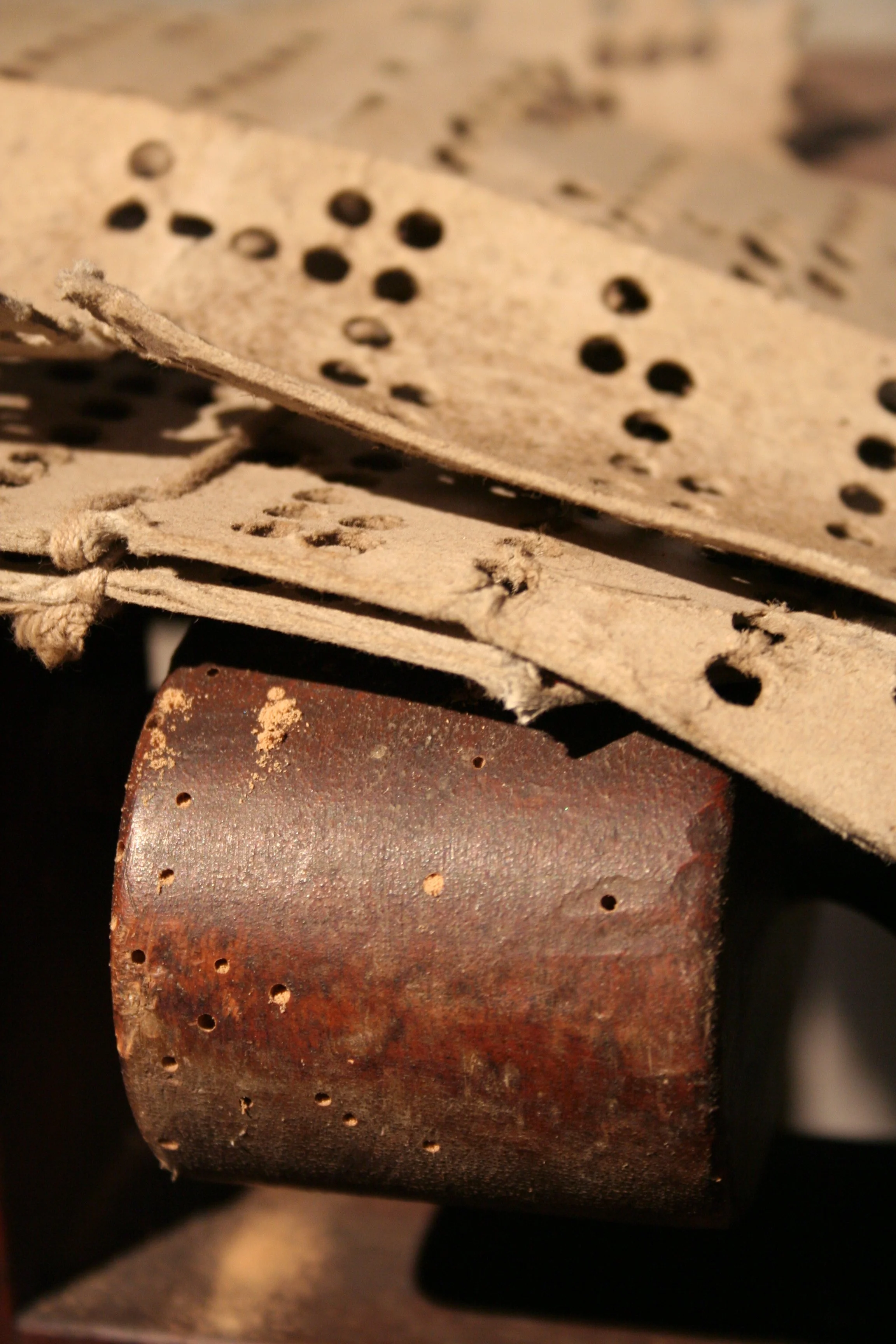 Close-up of an old, rusted iron block resting on a wooden surface, with detached pieces of paper or cardboard with holes, possibly used for printing or crafting, laid on top.