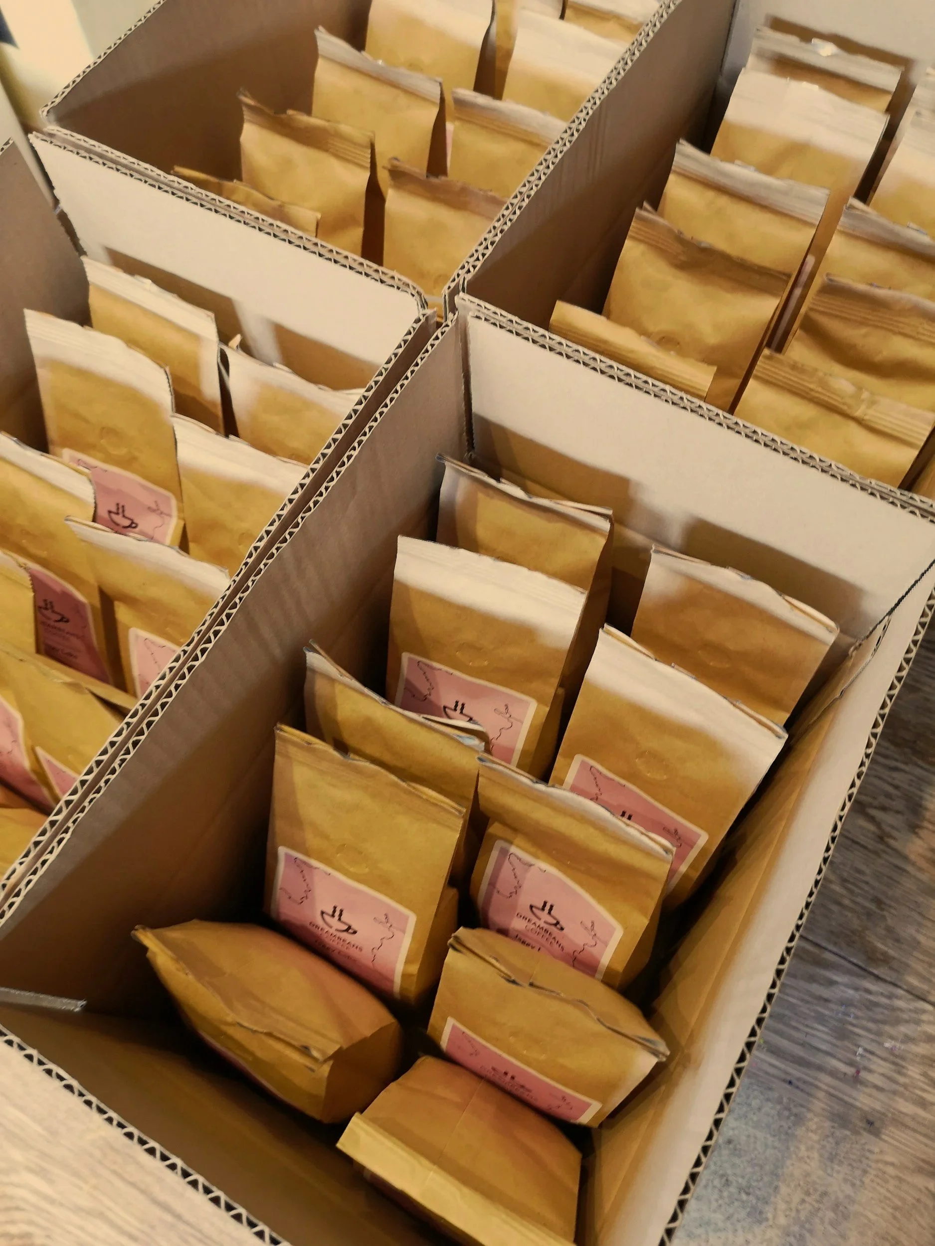 A cardboard box filled with multiple paper packets, some with pink labels, organized in rows.