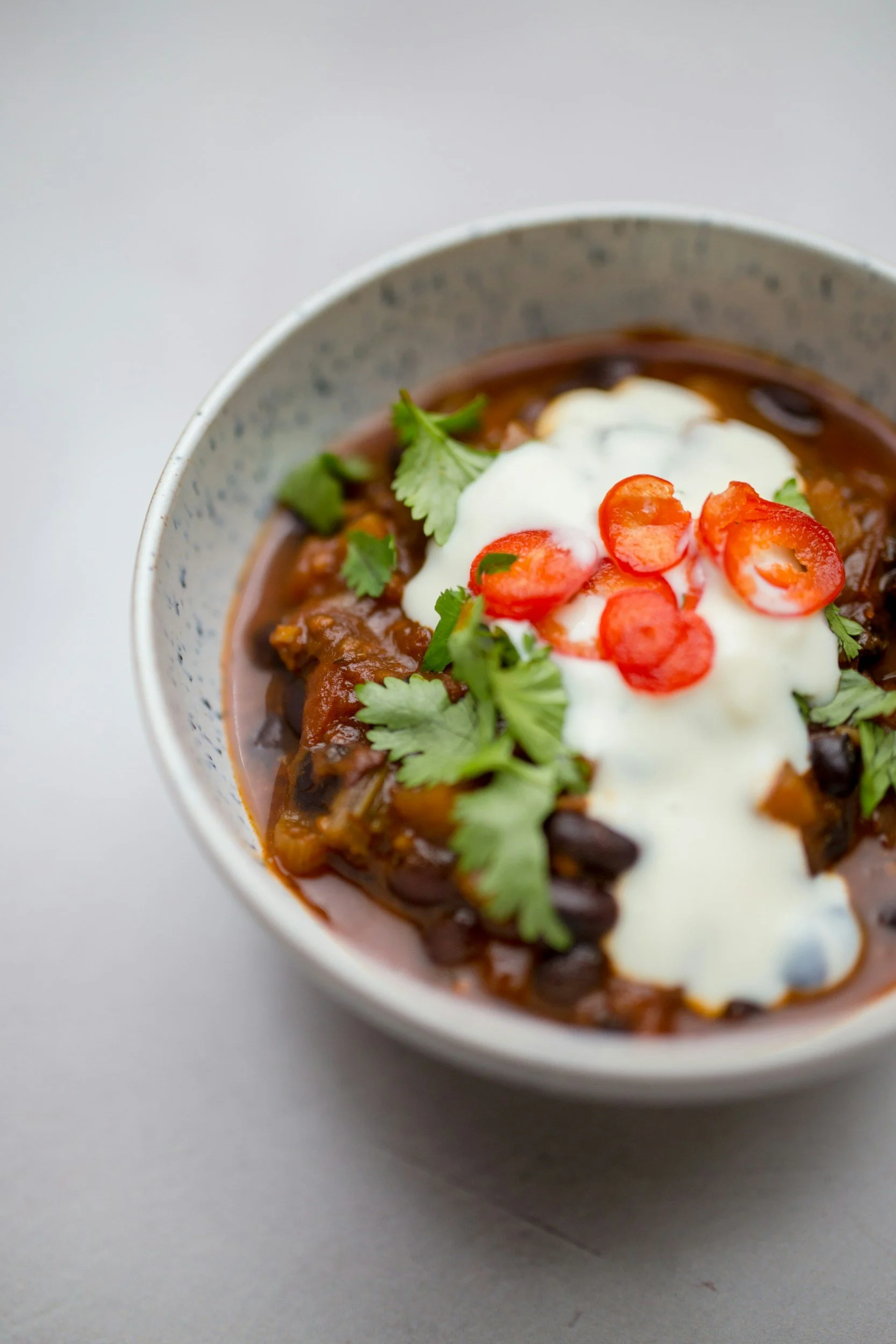 Bowl of slow-simmered chili topped with sour cream, onions, shredded cheese and jalapenos