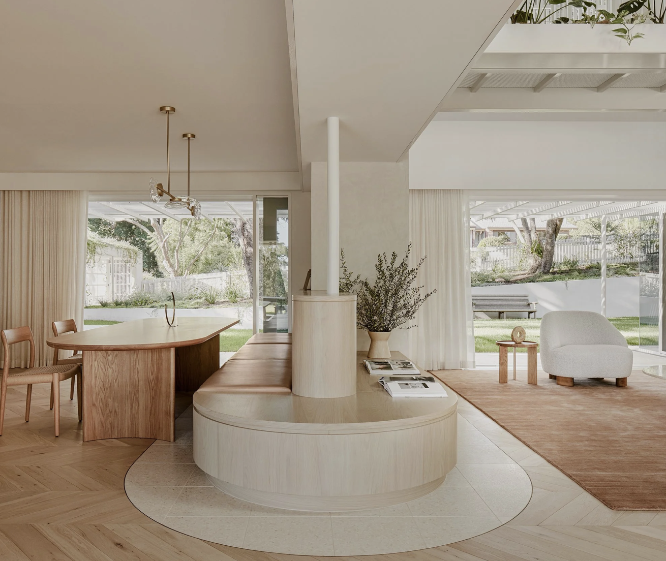 Modern living room with large windows, wooden furniture, white and beige decor, and a view of a garden outside.