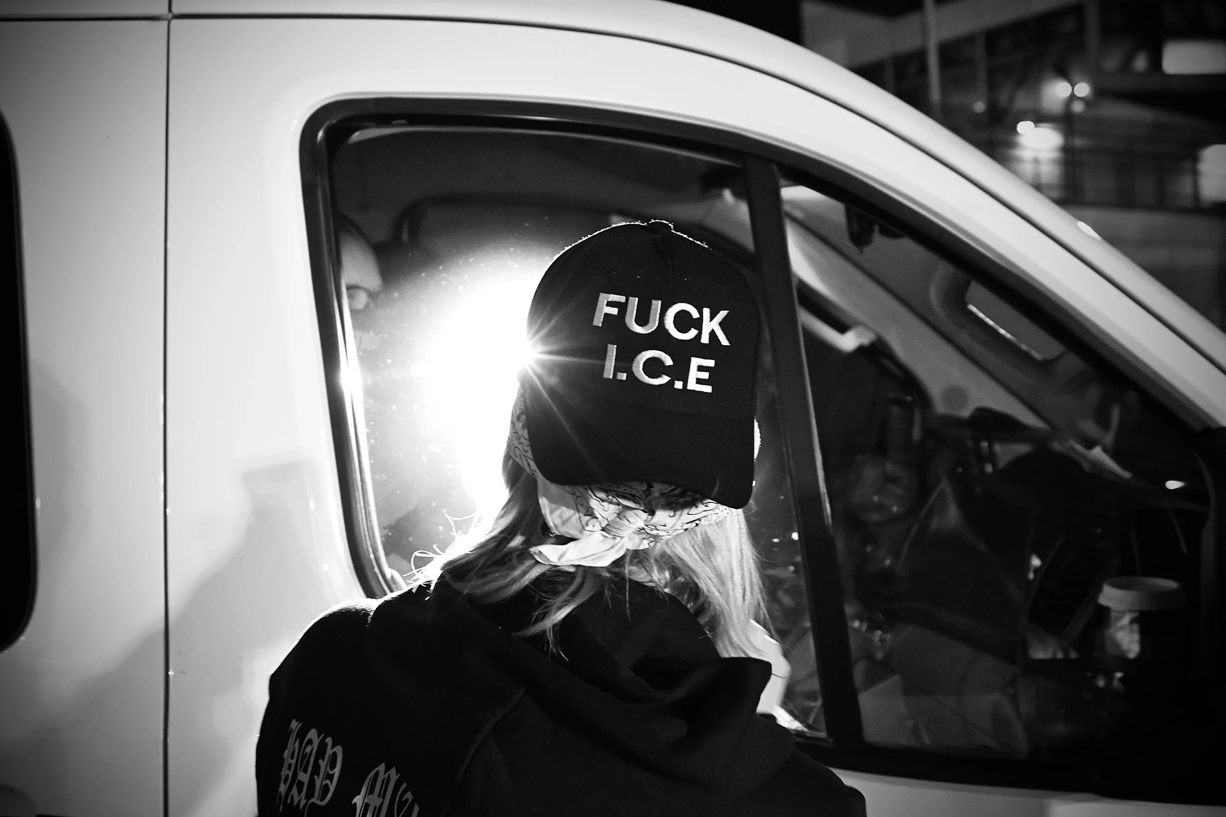 A protester shines a light on a car suspected of carrying arrested individuals, driven by ICE agents. (Los Angeles, 2025)