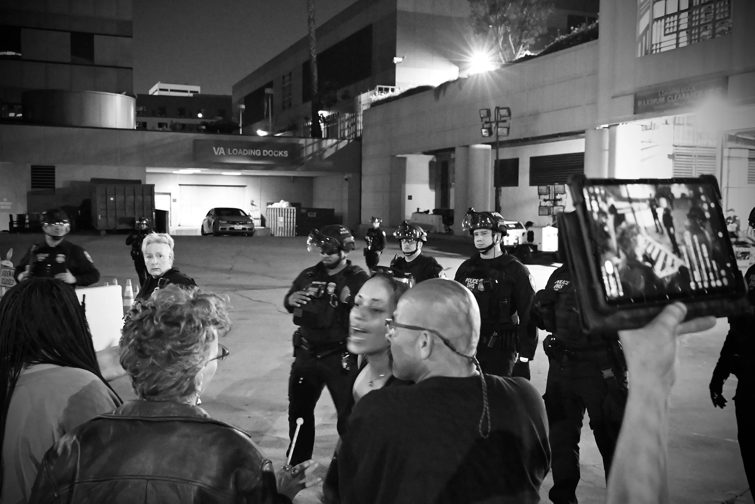DHS agents observe as protesters engage in a heated arguments over the approach and pace of the demonstration. (Los Angeles, 2025)