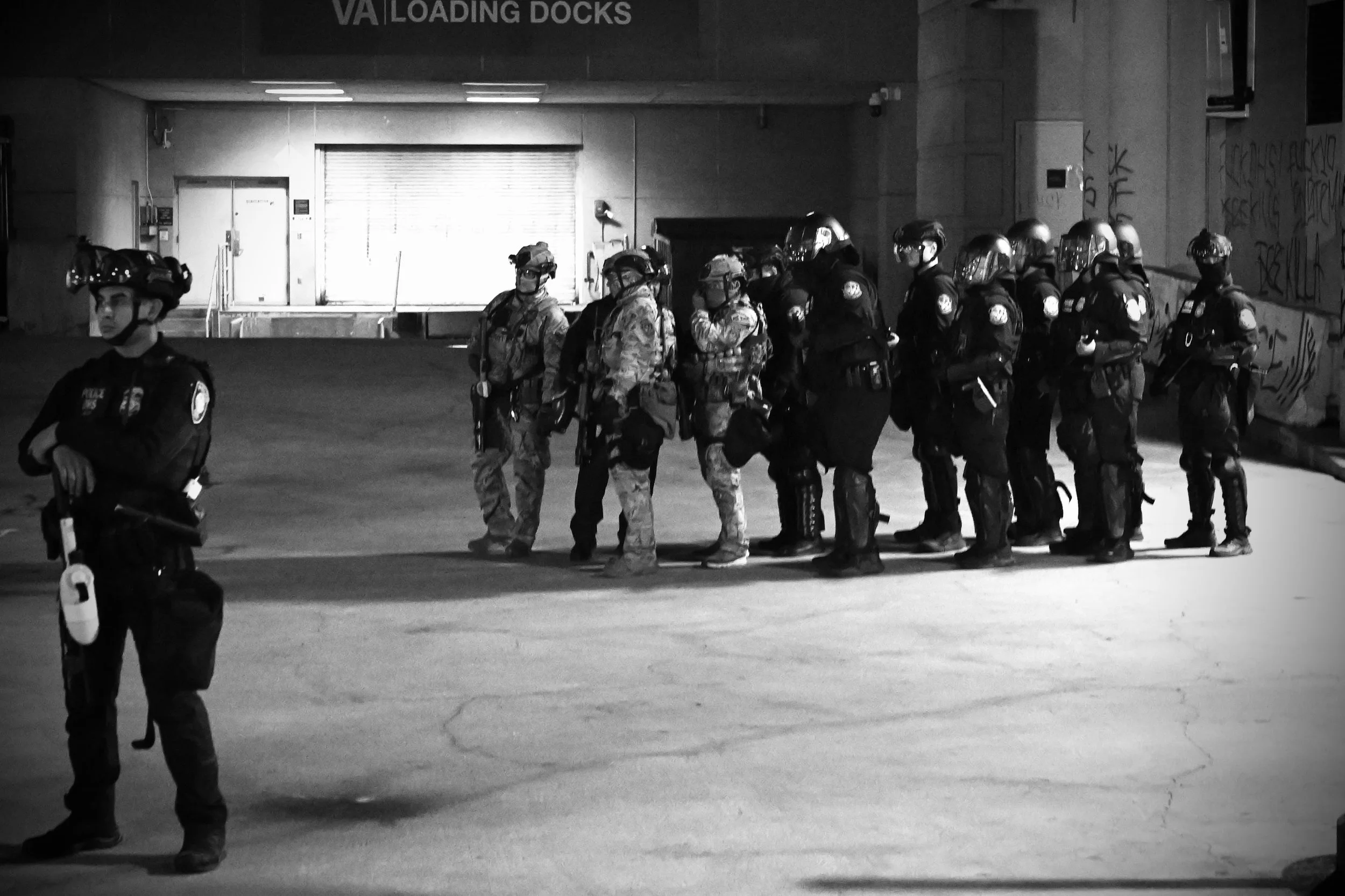 After the arrival of the BATT-X, ICE’s Special Response Team deploys and falls into formation, officers speaking quietly as they plan their approach toward the crowd. (Los Angeles, 2026)