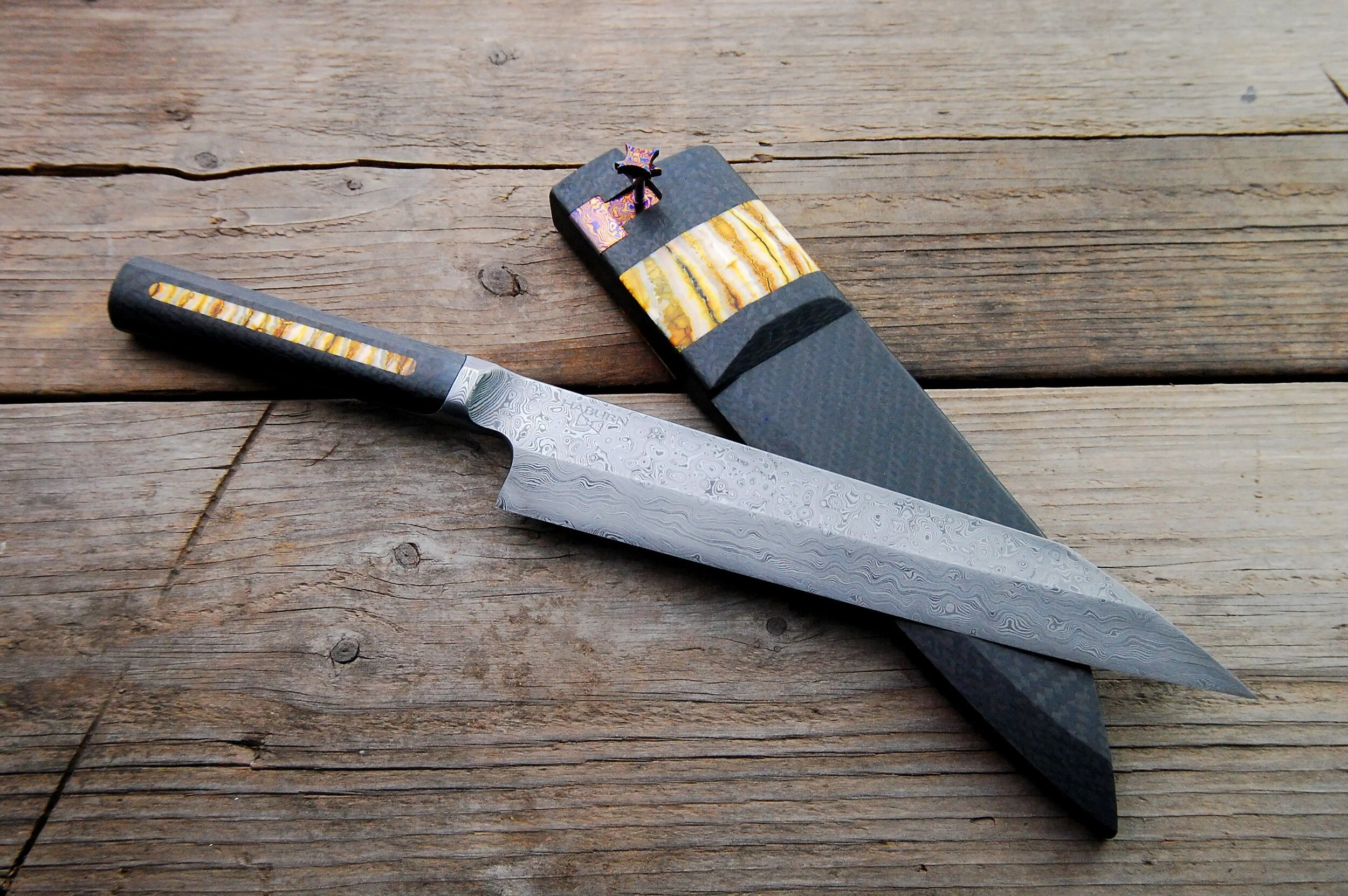Raindrop Damascus Full Tang Integral Kiritsuke custom chef knife - Carbon fiber and yellow mammoth tooth inlay on the handle.  Leather-lined, solid carbon fiber saya with inlay in yellow mammoth-tooth and Timascus and a threaded Timascus keeper pin.