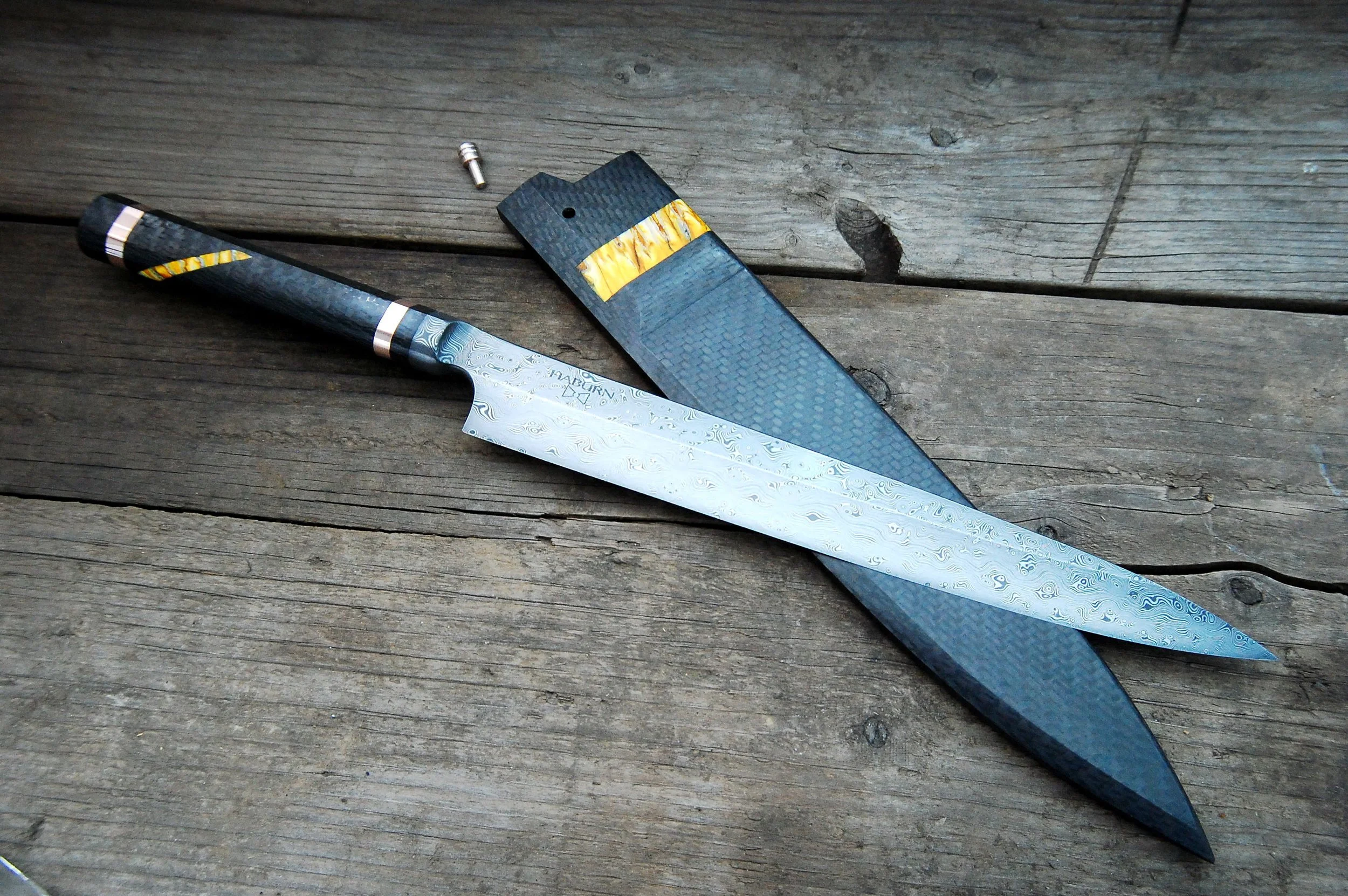 Raindrop Damascus Yanagiba Integral custom chef knife - This 270mm custom yanagiba features raindrop damascus, a hand-forged integral bolster, and handled in carbon fiber with mammoth tooth and mokume gane spacers.  The saya is solid carbon fiber wit