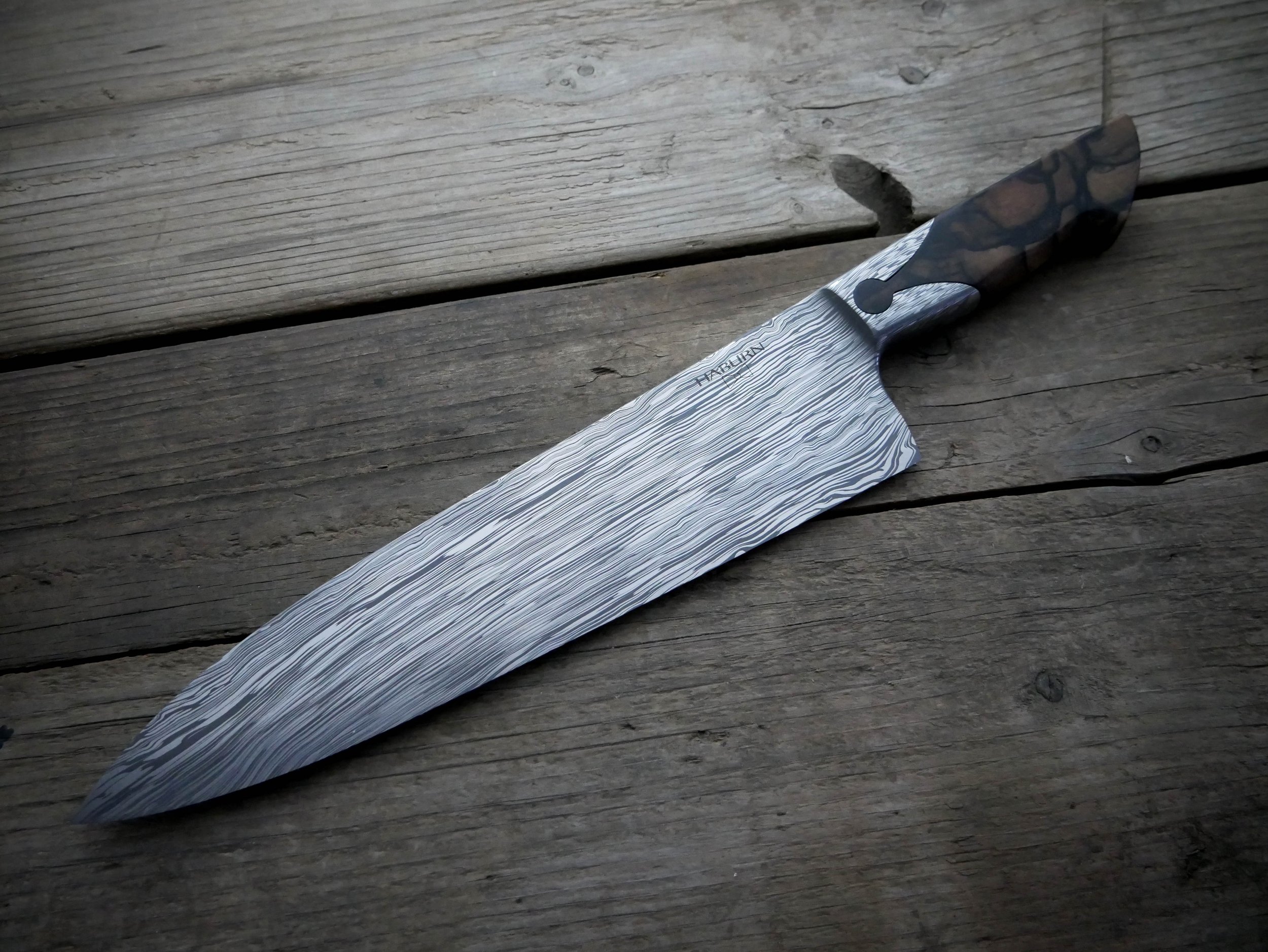 This extra large gyuto was commissioned by a previous customer. I moved the keyhole closer to the front of the bolster to reduce handle weight for a more nimble feel. The stainless damacus is made from about 56% AEB-L and 44% CPM154 in my Midnight Ri