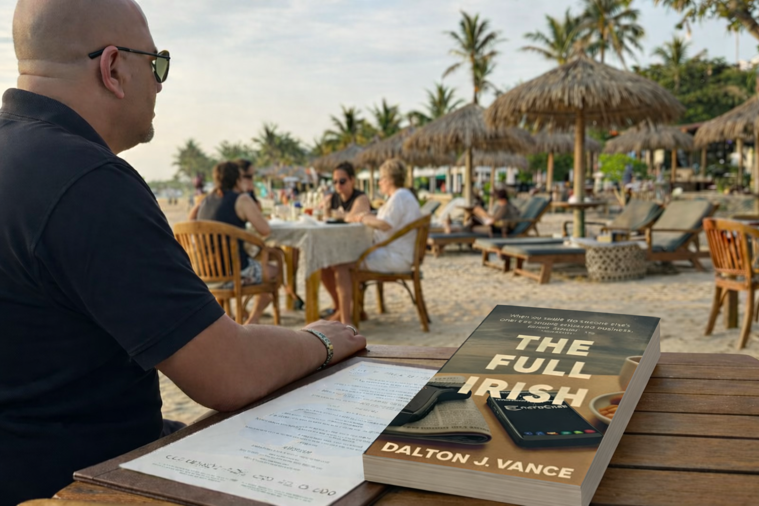 A person sitting at an outdoor beachside restaurant reading a book titled 'The Full Irish' by Dalton J. Vance, with a menu and a phone on the table.