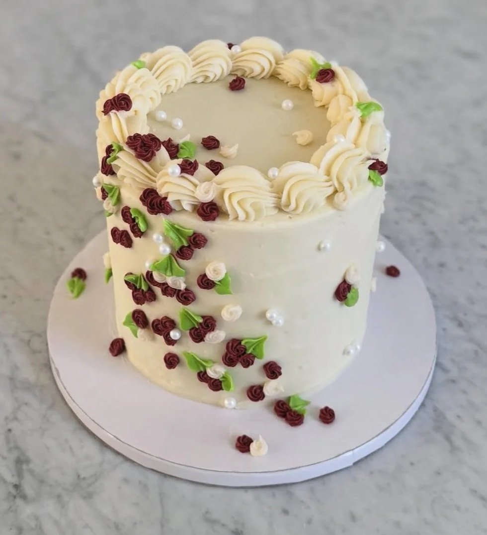  Rosey Bloom   
A rich pistachio cake with cream cheese buttercream, decorated elegantly with red roses and pearly accents. 