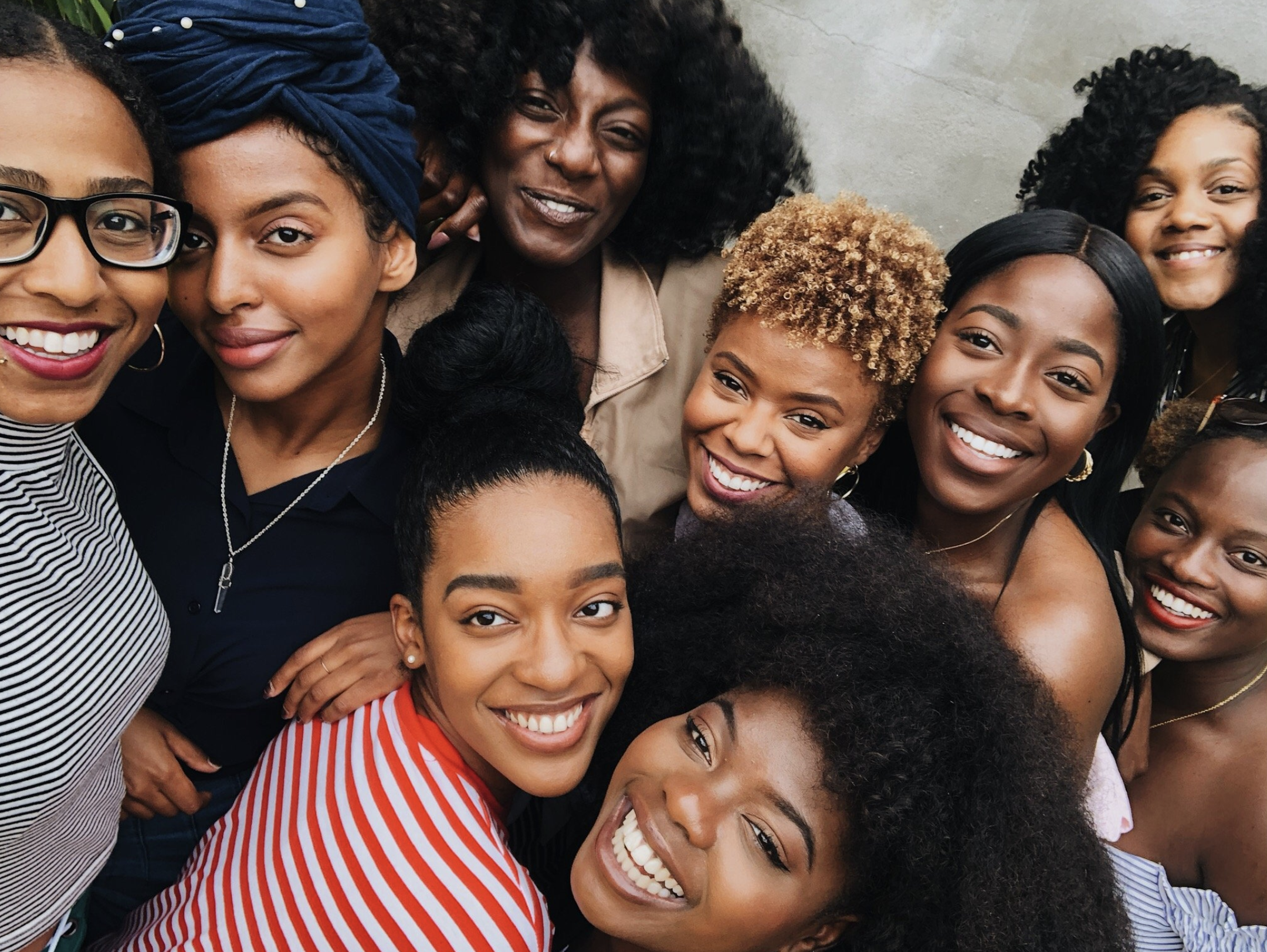 A group of smiling women of African descent taking a close-up selfie together.