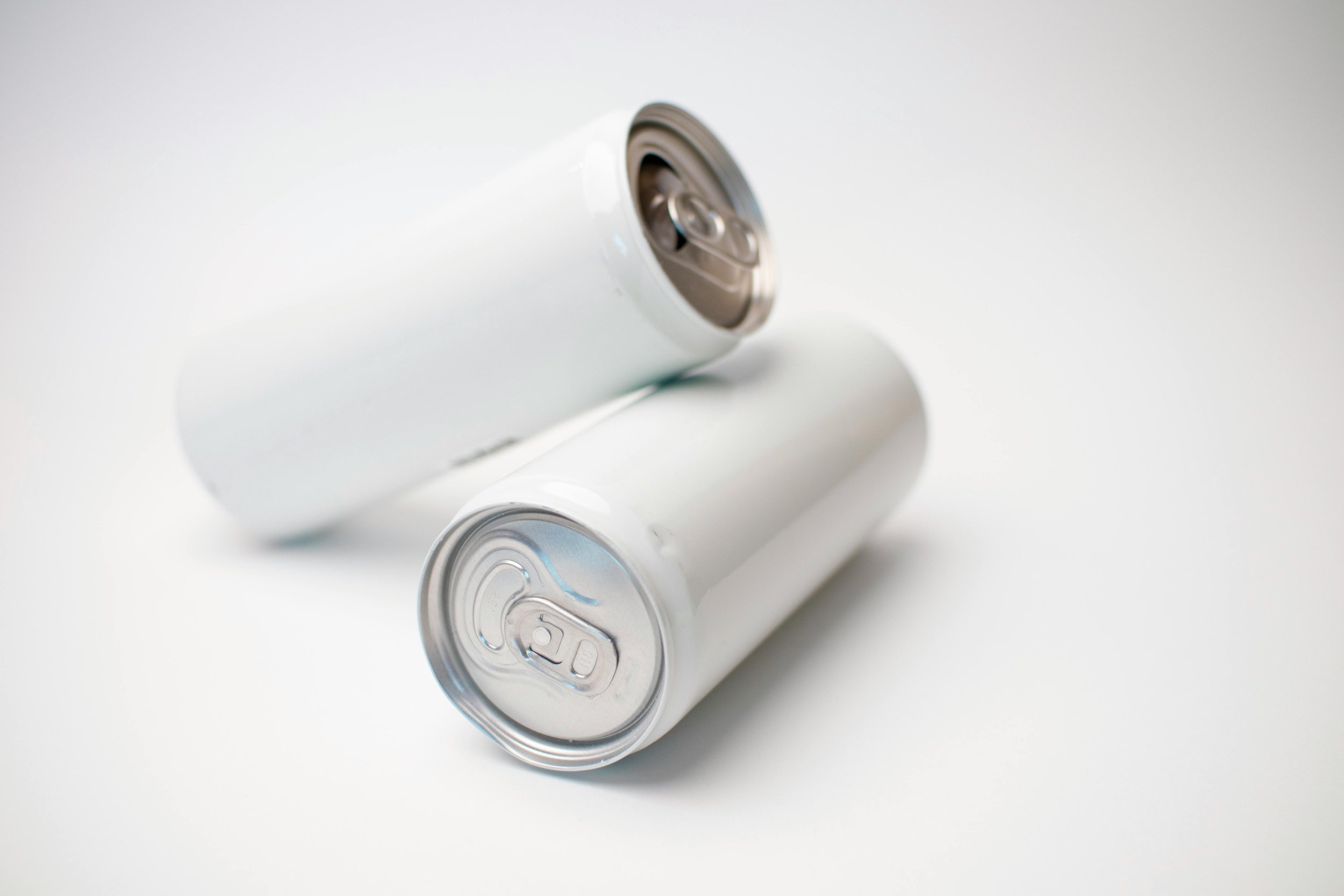 Two white aluminum cans, one lying down and one standing, on a white surface.