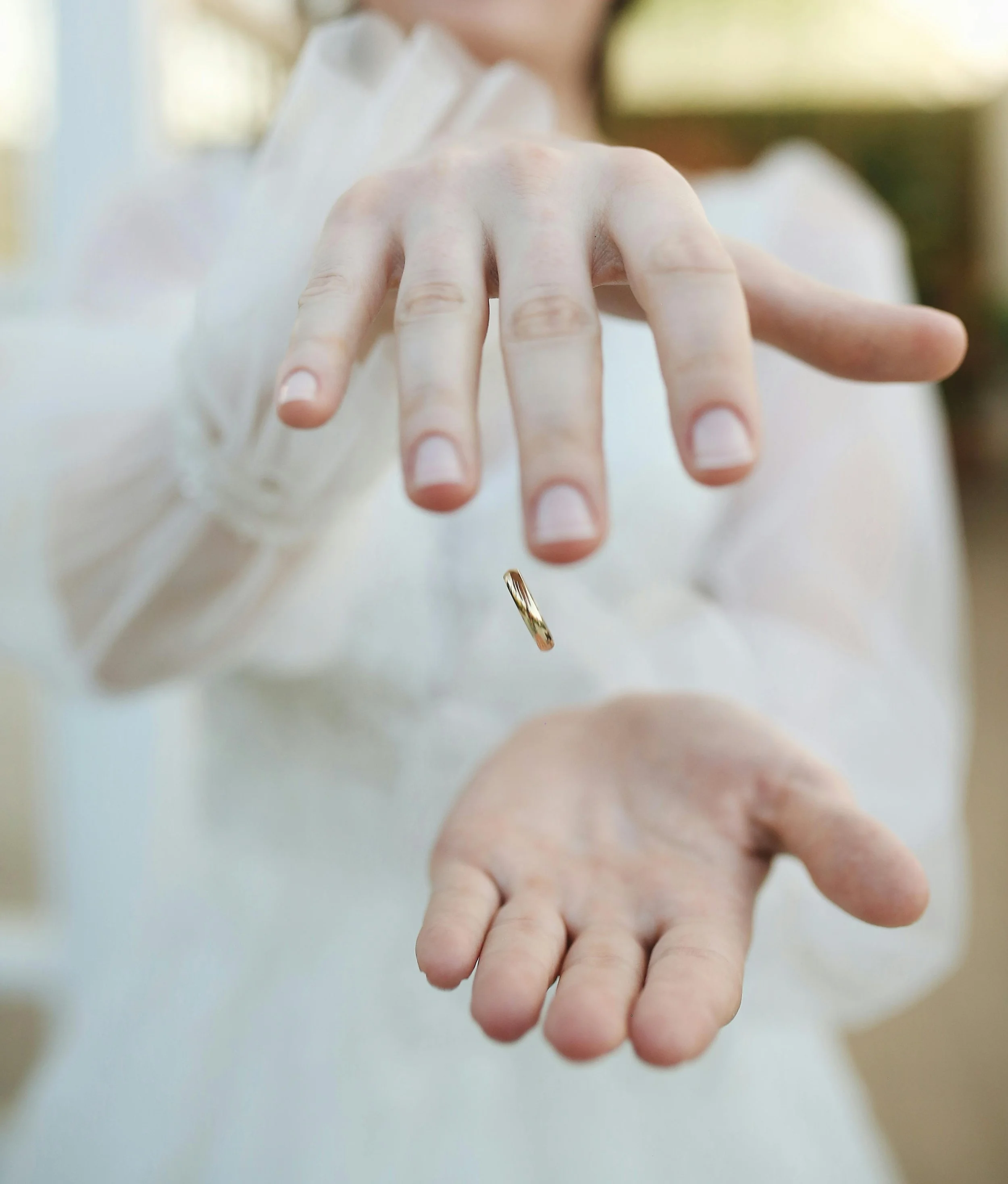 Person releasing a gold ring from their hand, with an open palm below.