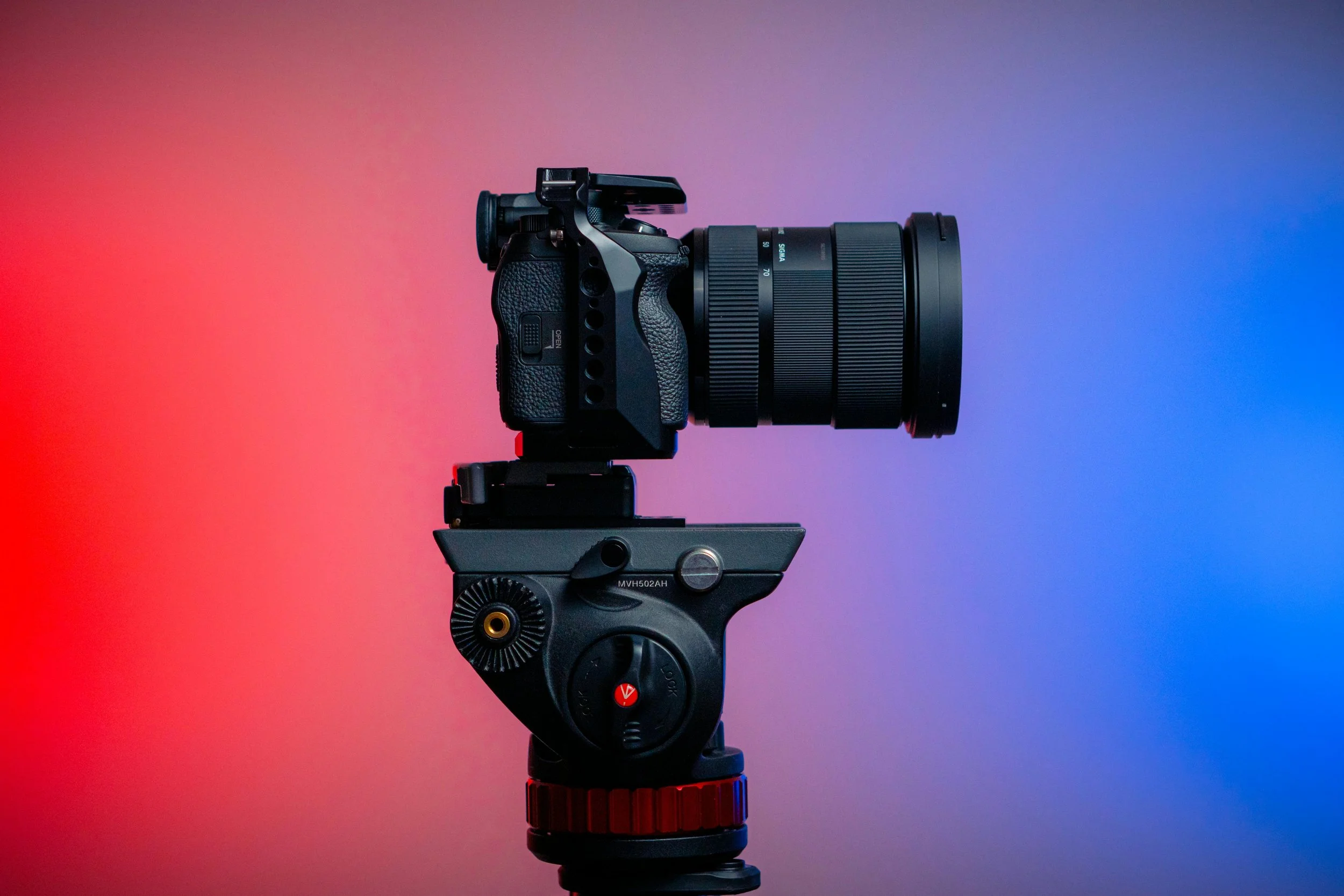 Camera mounted on a tripod against a colorful gradient background.
