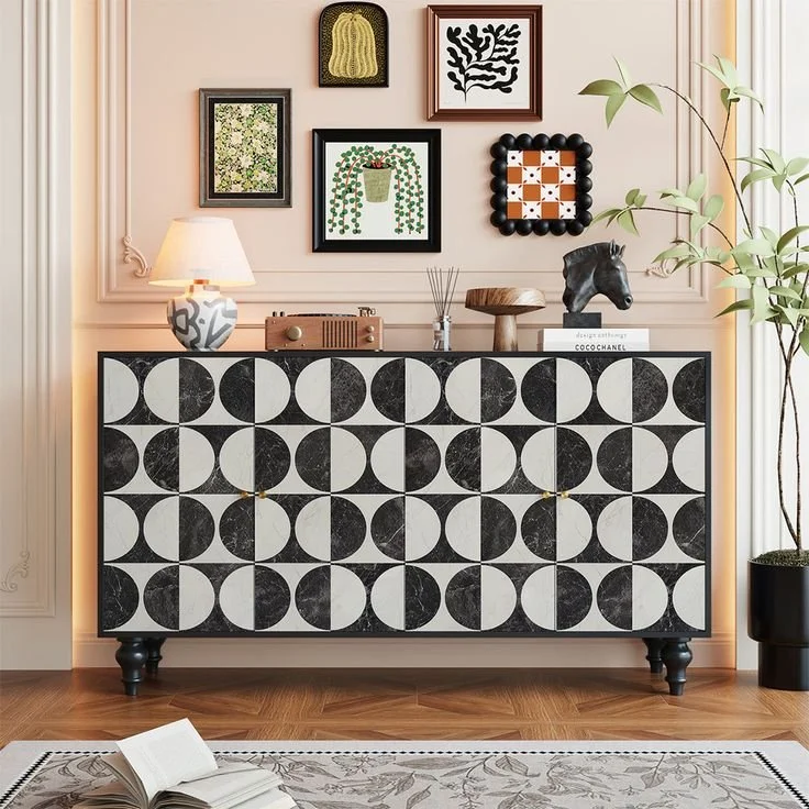 Decorative black and white checkered cabinet in a living room with framed art on the wall, a lamp, and a plant.