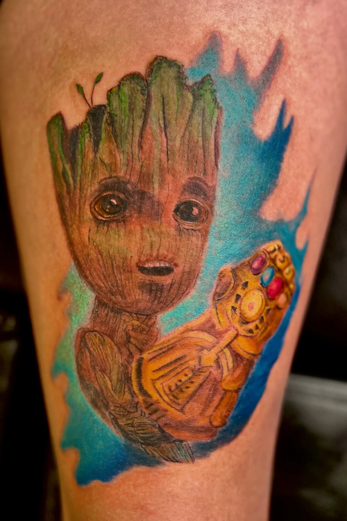 Tattoo of Baby Groot holding a Liberty Walk telephone, with a blue background.