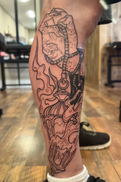Black outline tattoo of a dog with a braided leash on a person's lower leg, with abstract flame-like designs and a tiki torch at the bottom.