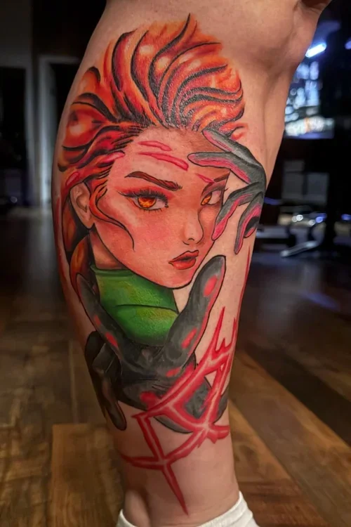 Tattoo of a woman with fiery red and orange hair, piercing orange eyes, and a green collar, surrounded by dark and red abstract elements on a person's upper arm.