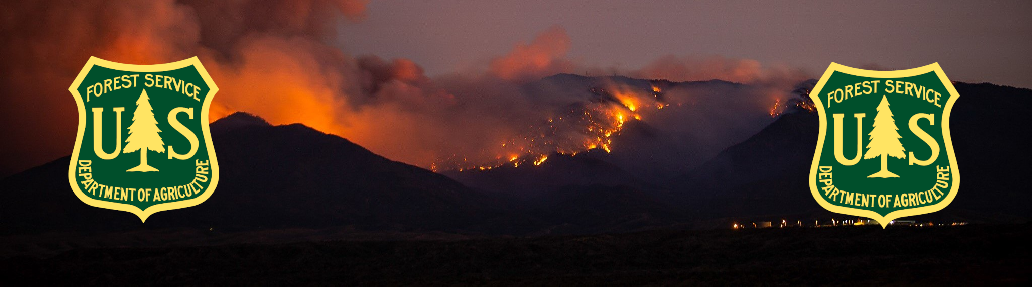 Wildfire burning on mountains with smoke and flames, two US Forest Service patches overlapping the scene.