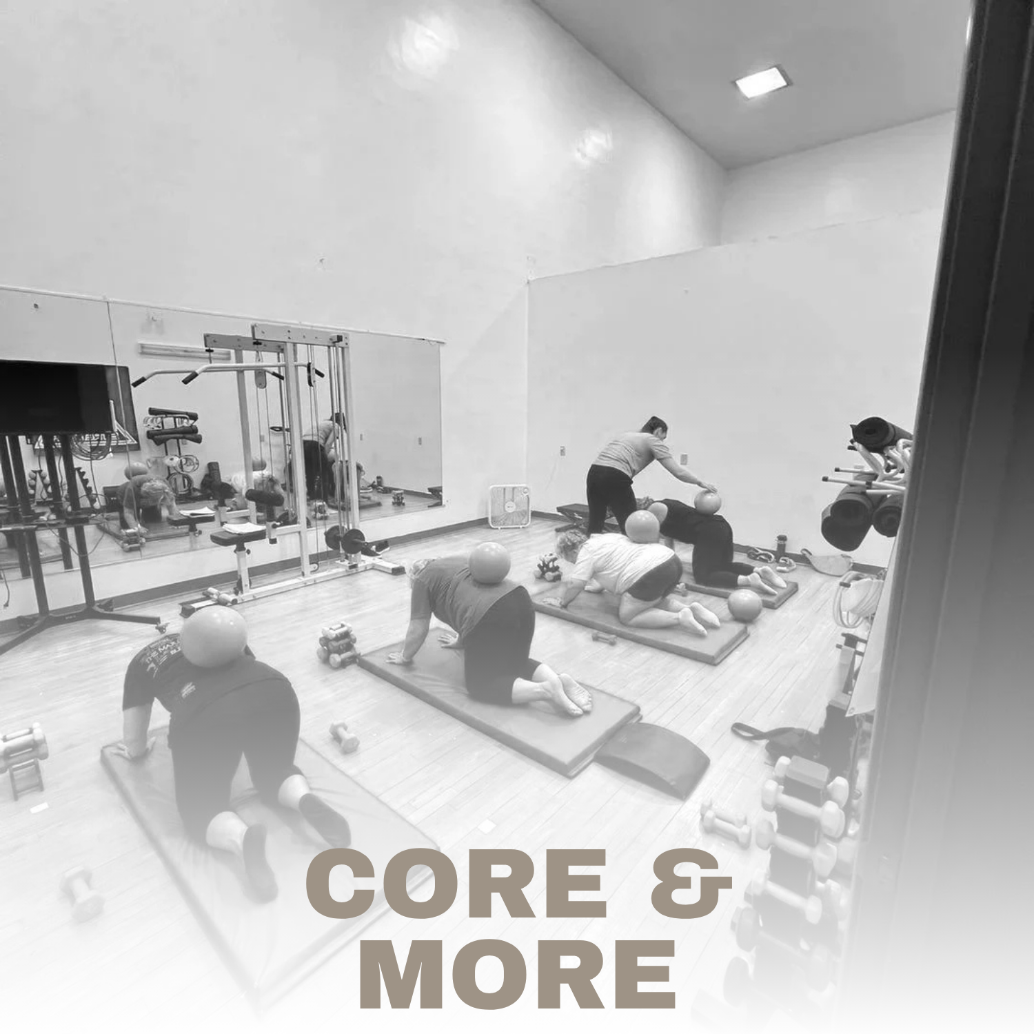 People participating in a fitness class doing core exercises on mats in a gym, with weights and exercise equipment visible.