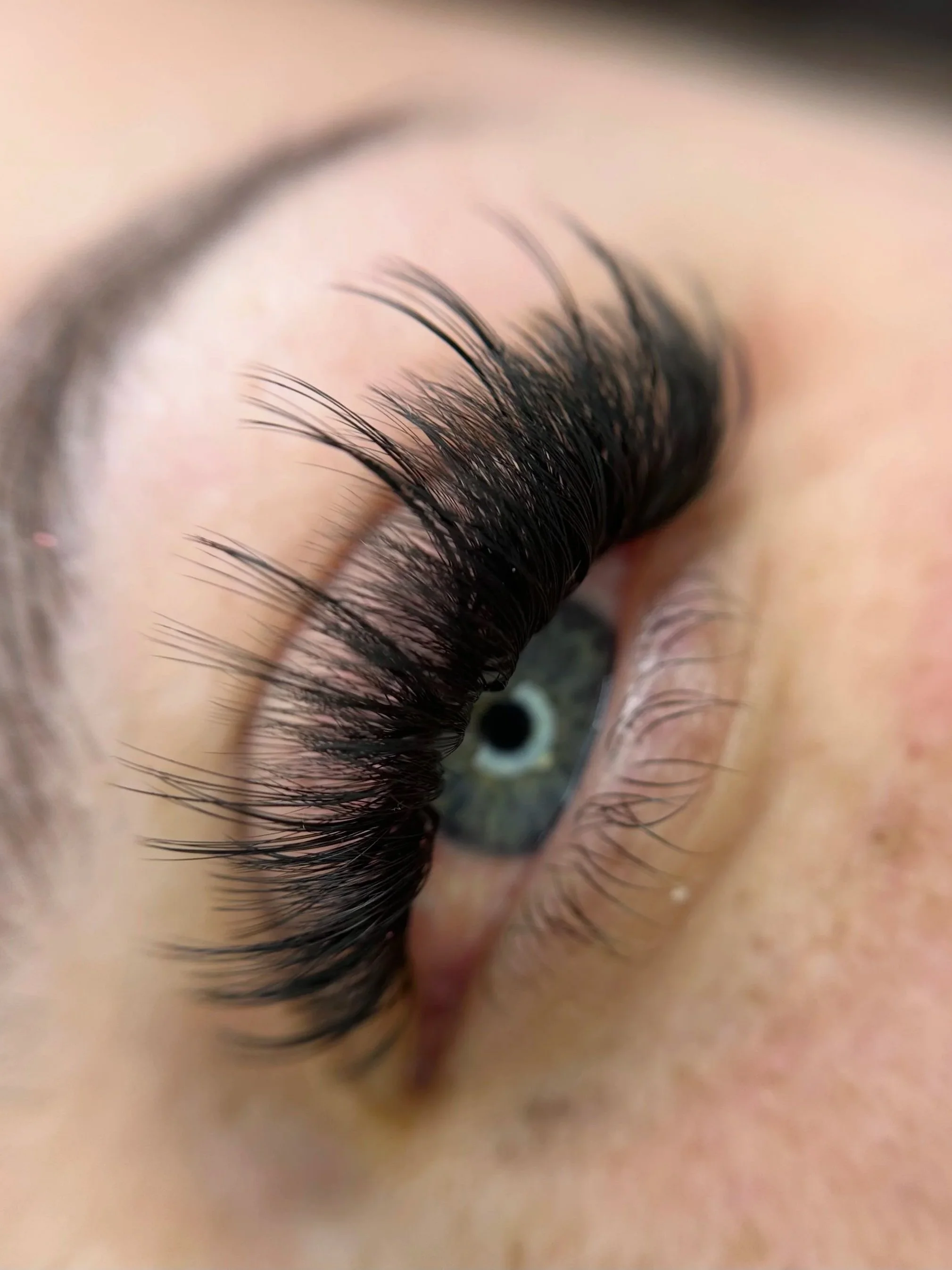 Close-up of a strip lash extension style with blue iris.