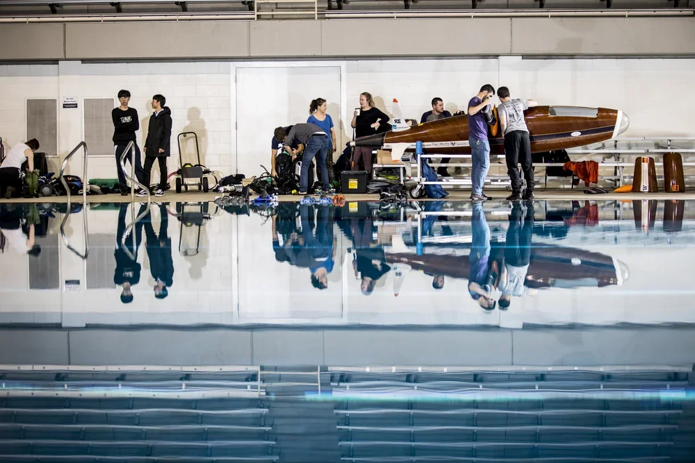 People preparing a submarine at an indoor swimming pool