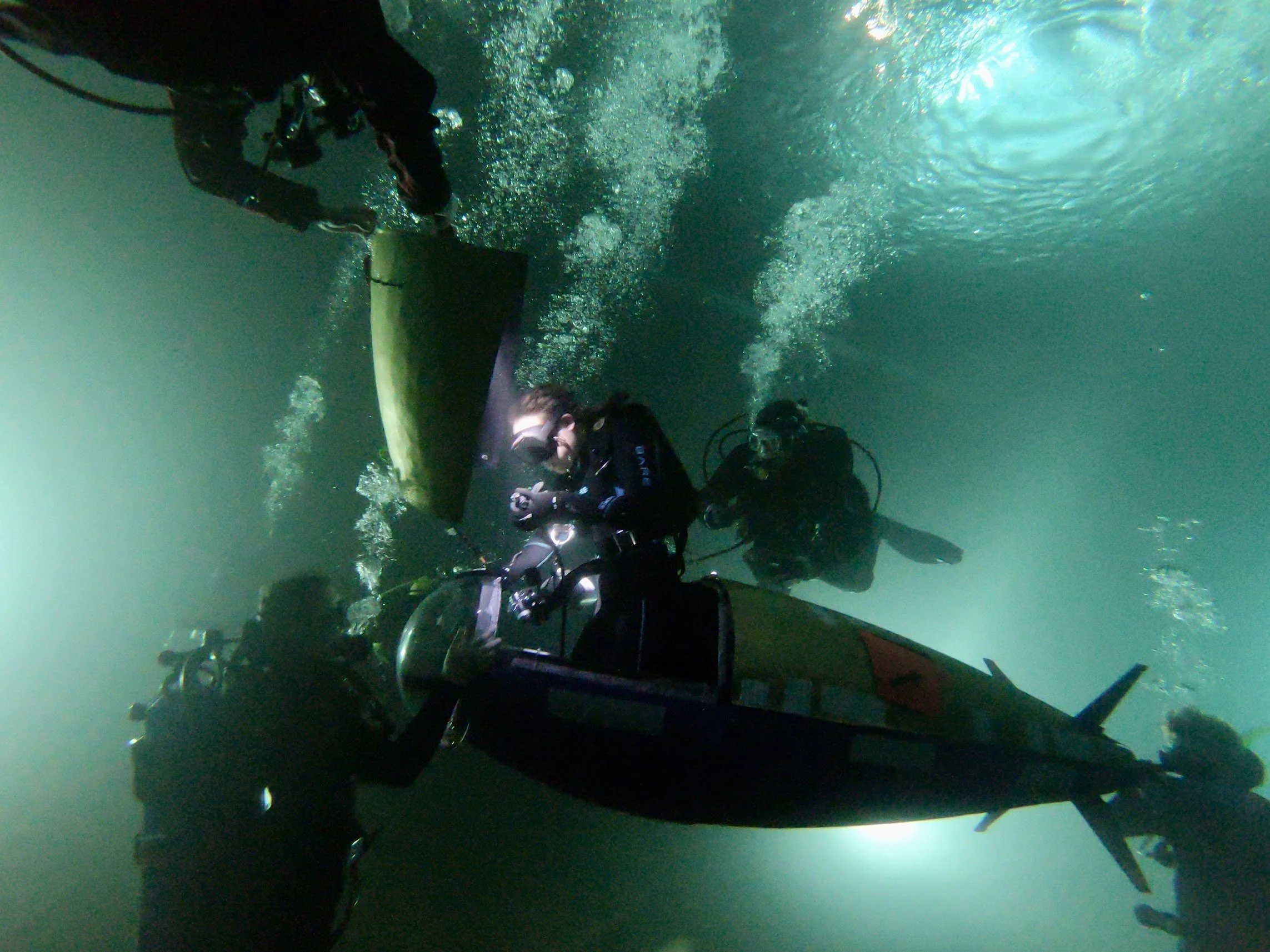 Pilot entering Subwoofer as three support divers surround her