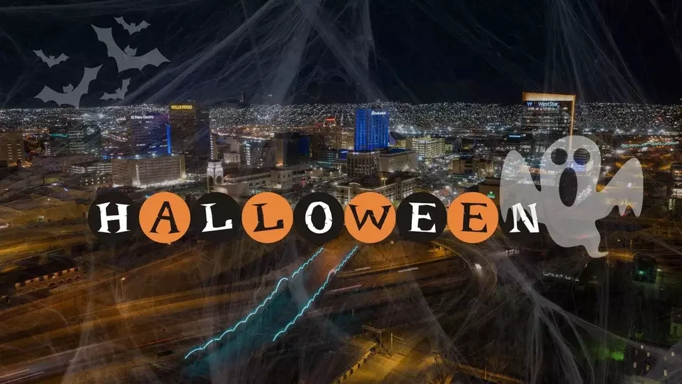 Nighttime cityscape decorated with a Halloween theme, featuring a string of letters spelling 'HALLOWEEN' in black and orange circles, a ghost figure, and bats against a dark sky.