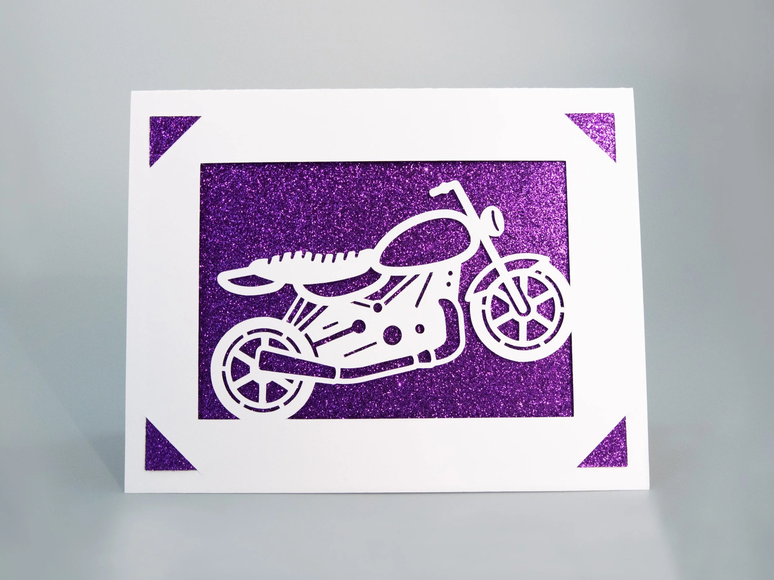 Front view of a greeting card with a motorcycle cutout and purple glitter background