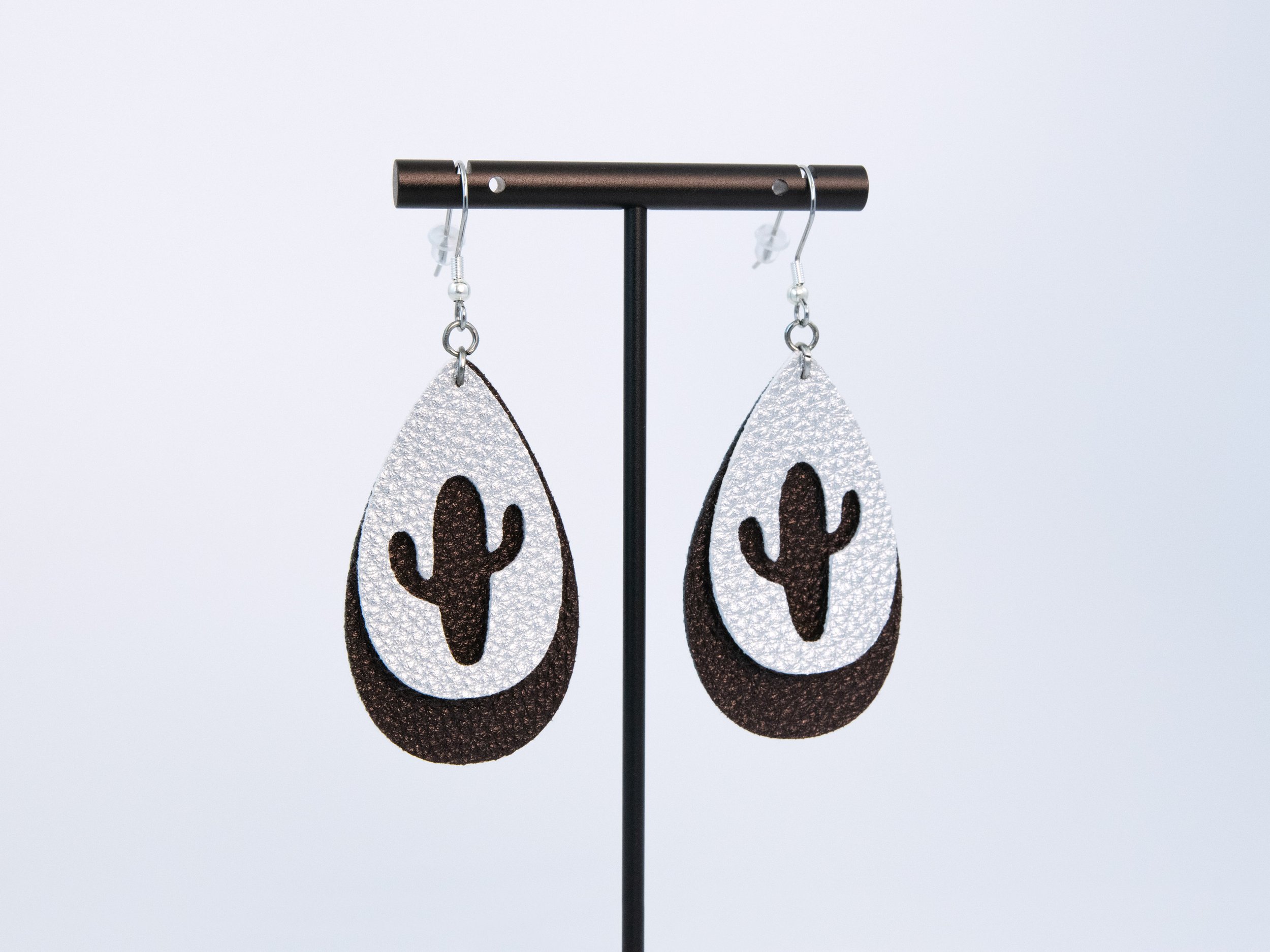 Cactus teardrop earrings on a T-bar display stand. The earrings have layered dark brown and silver faux leather with silver-finished hooks