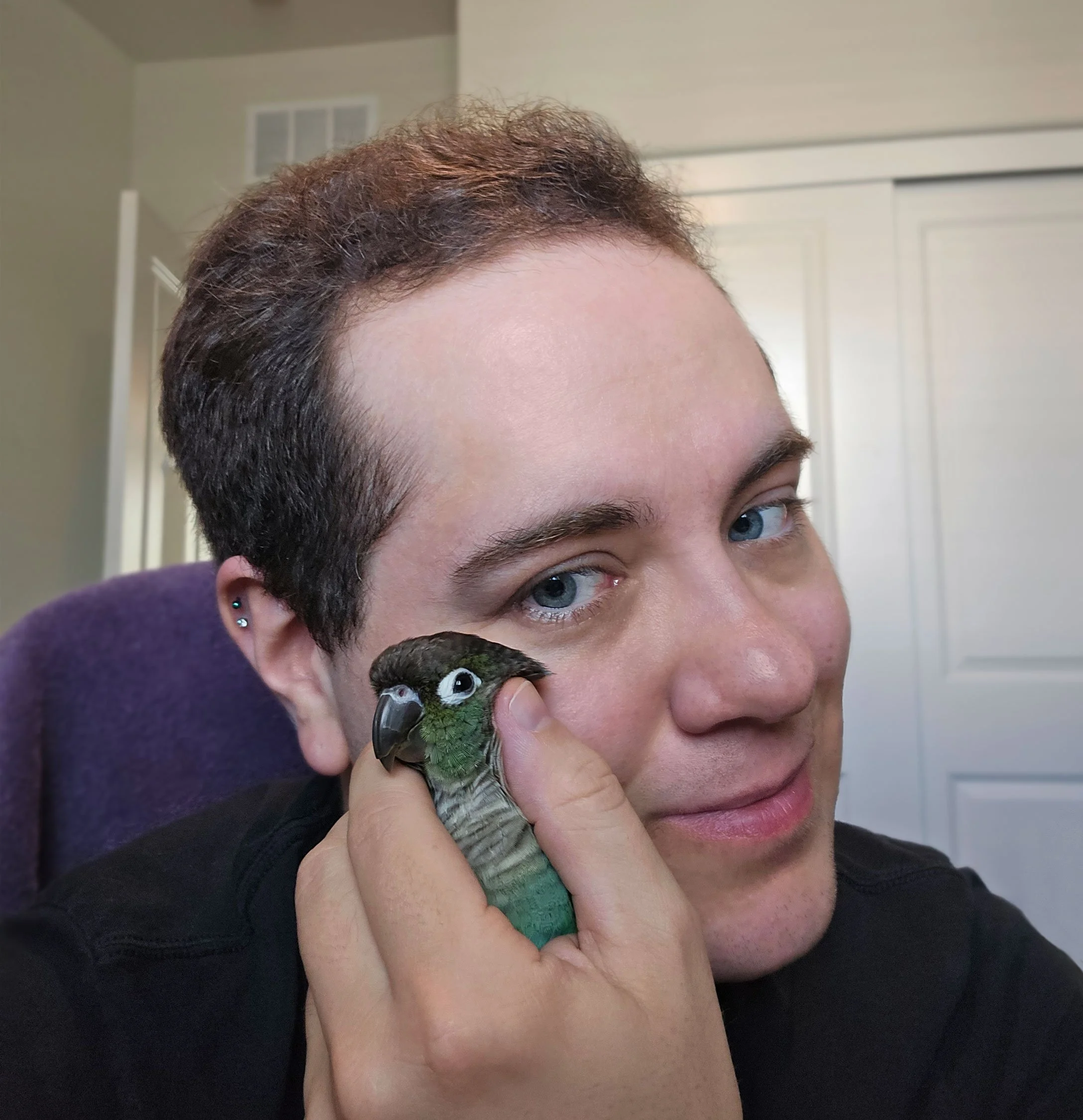 Marcel Nehlsen holding Pancake, the green-cheeked conure