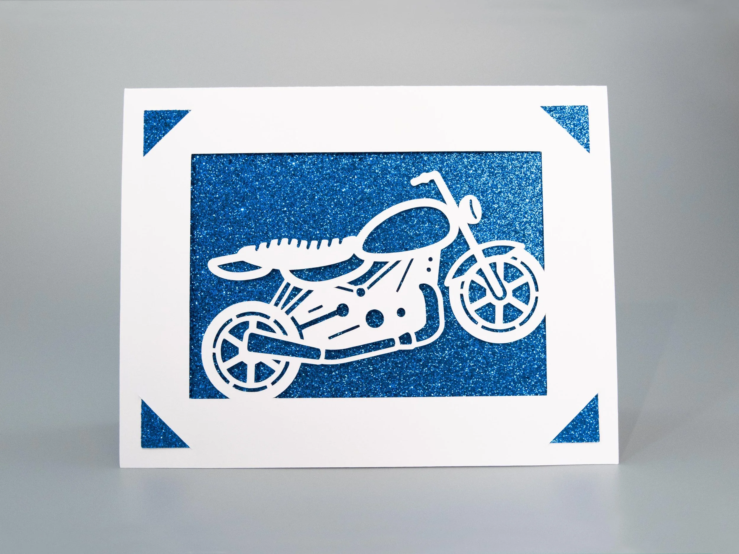 Front view of a greeting card with a motorcycle cutout and blue glitter background