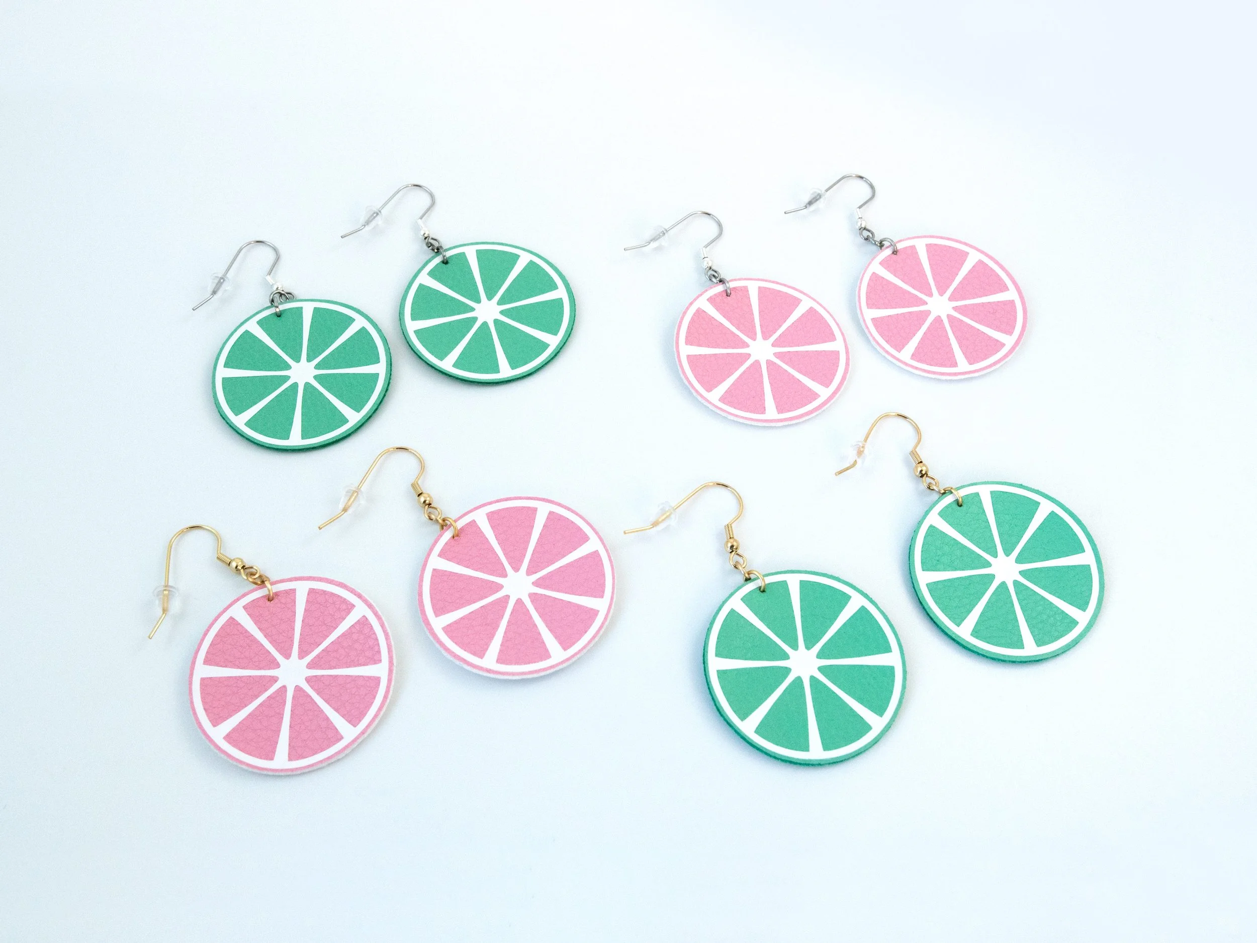 Angled view of all faux leather and hook color combinations for citrus earrings: green with gold hooks, green with silver hooks, pink with gold hooks, and pink with silver hooks