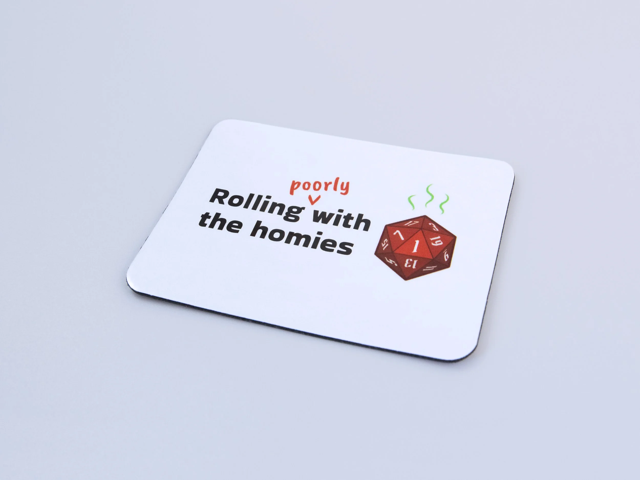 Zoomed in and angled view of a magnet. The design is a red d20 die with text that says “Rolling poorly with the homies”