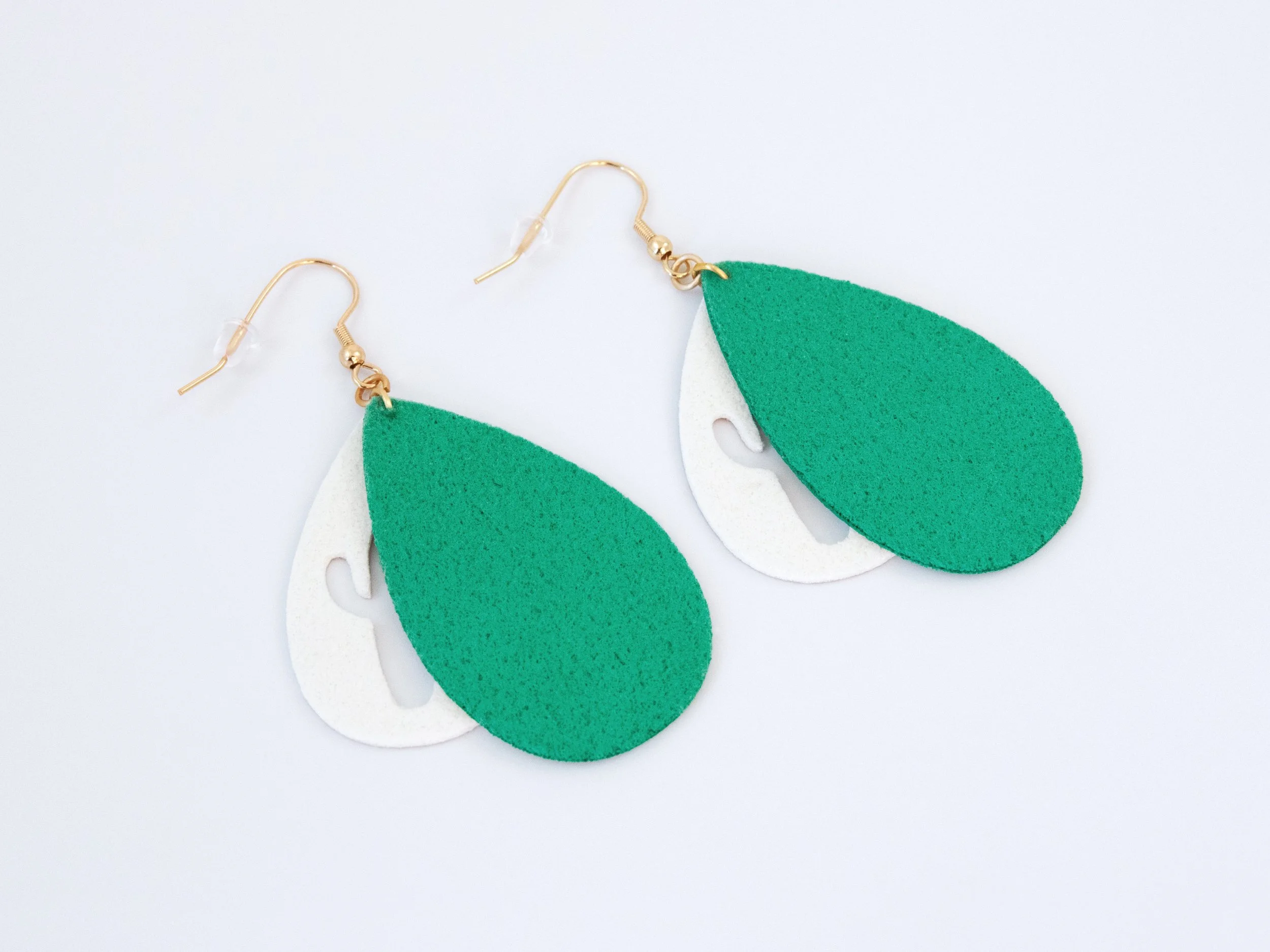 Green and gold cactus teardrop earrings that have been flipped over. Gold faux leather has white fabric on the back, while green faux leather has green fabric on the back