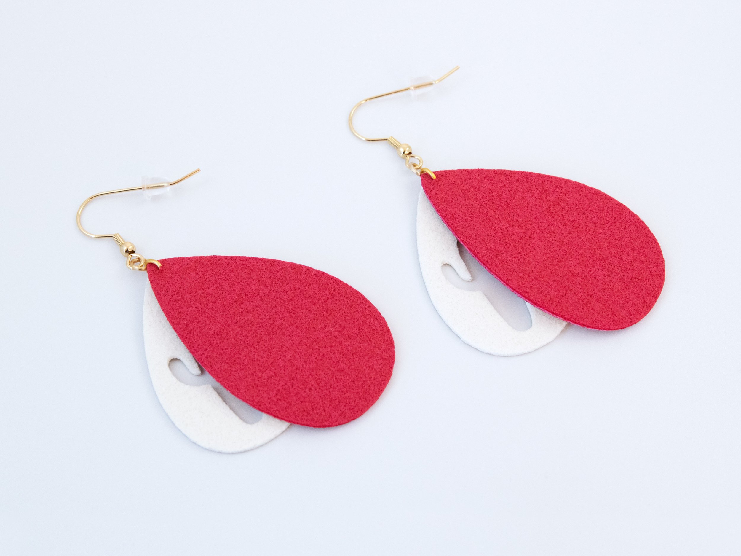 Red and gold cactus teardrop earrings that have been flipped over. Gold faux leather has white fabric on the back, while red faux leather has red fabric on the back
