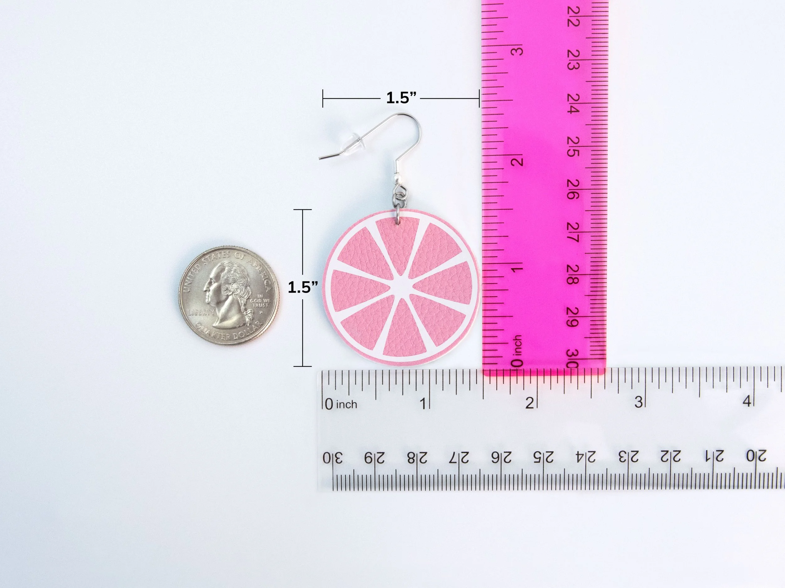 A round citrus earring next to rulers and a quarter to show scale. The faux leather circle has a 1.5” diameter