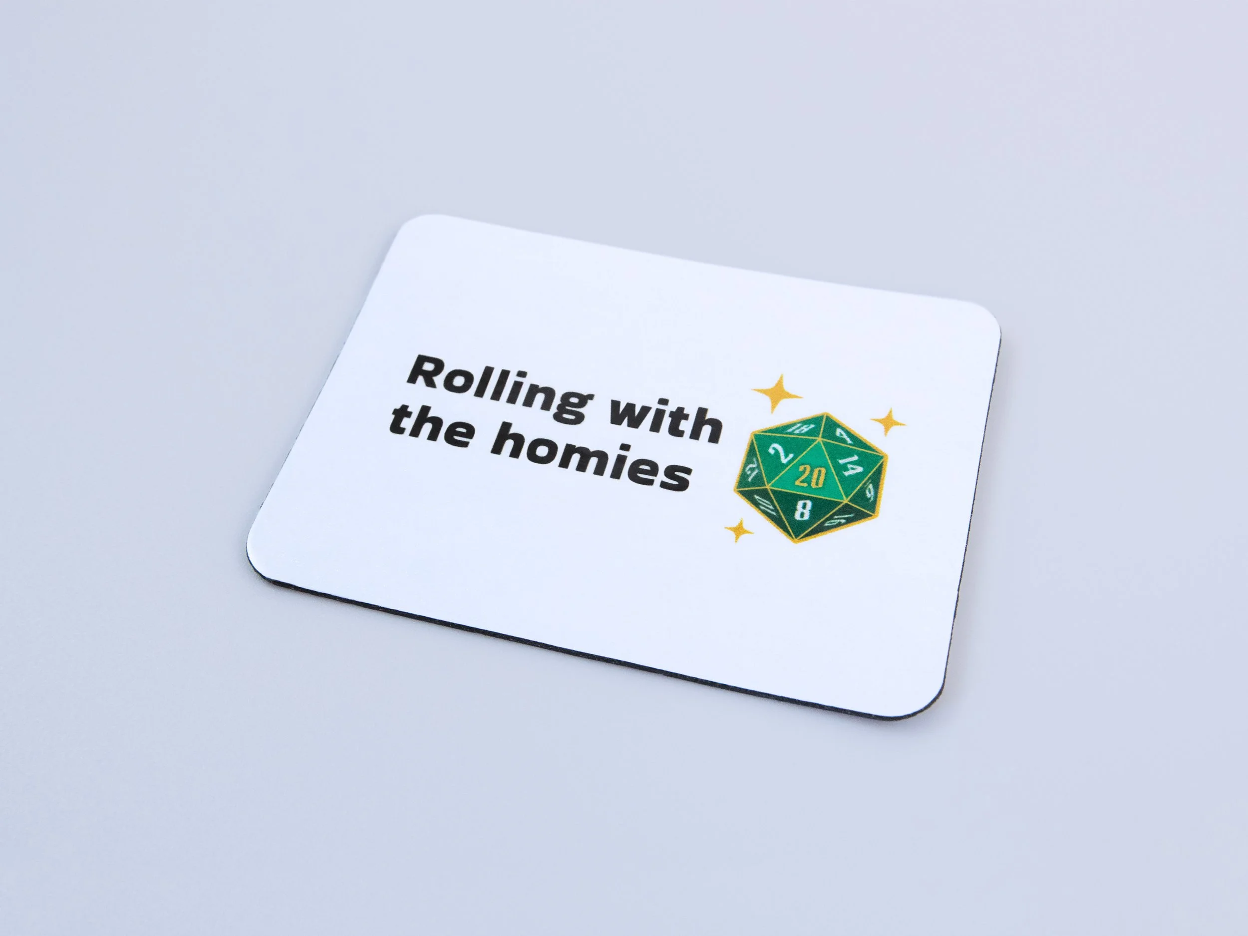 Zoomed in and angled view of a magnet. The design is a green d20 die with text that says “Rolling with the homies”