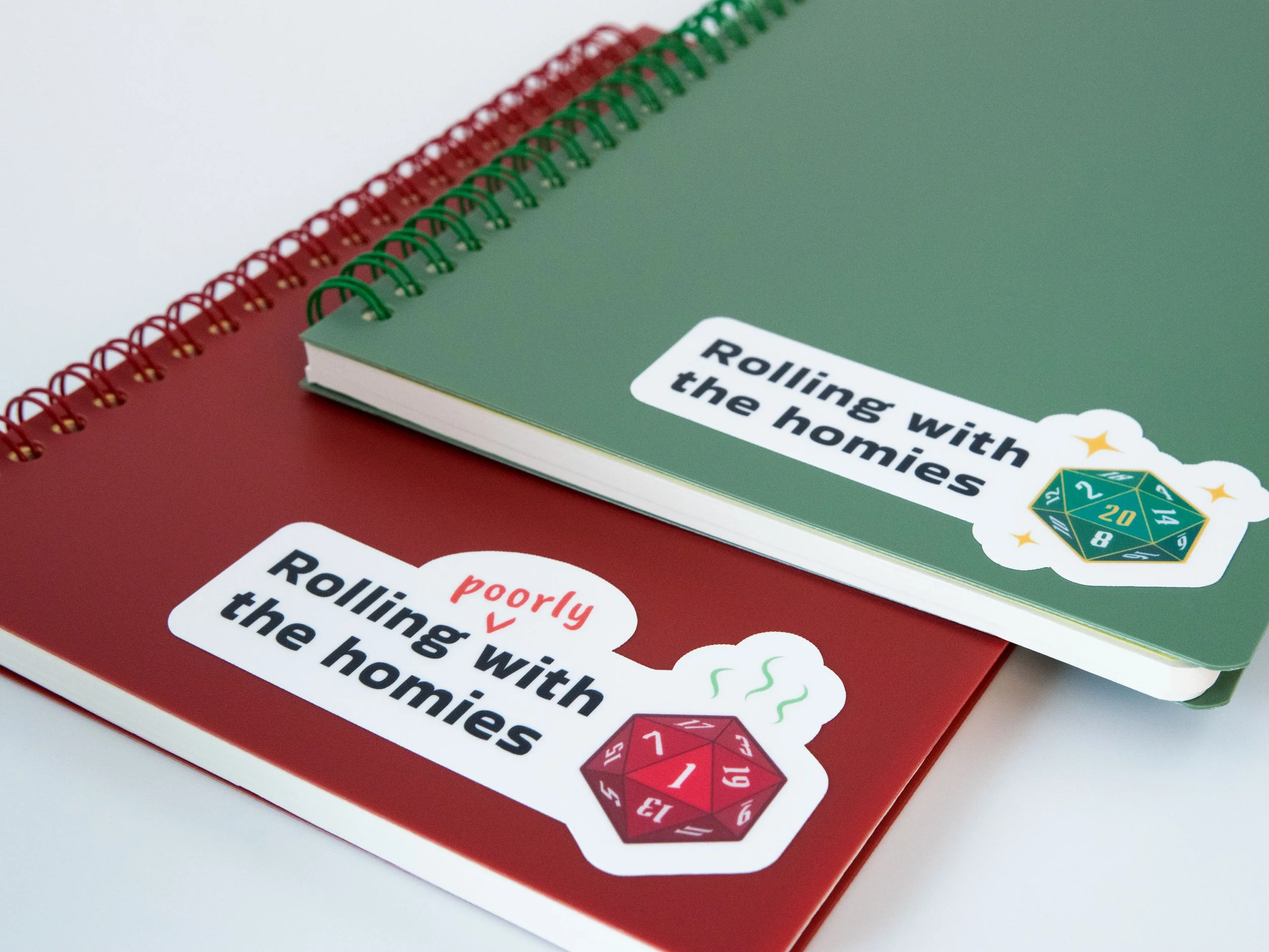 Stickers on small notebooks. One sticker says "Rolling with the homies," while the other says "Rolling poorly with the homies"