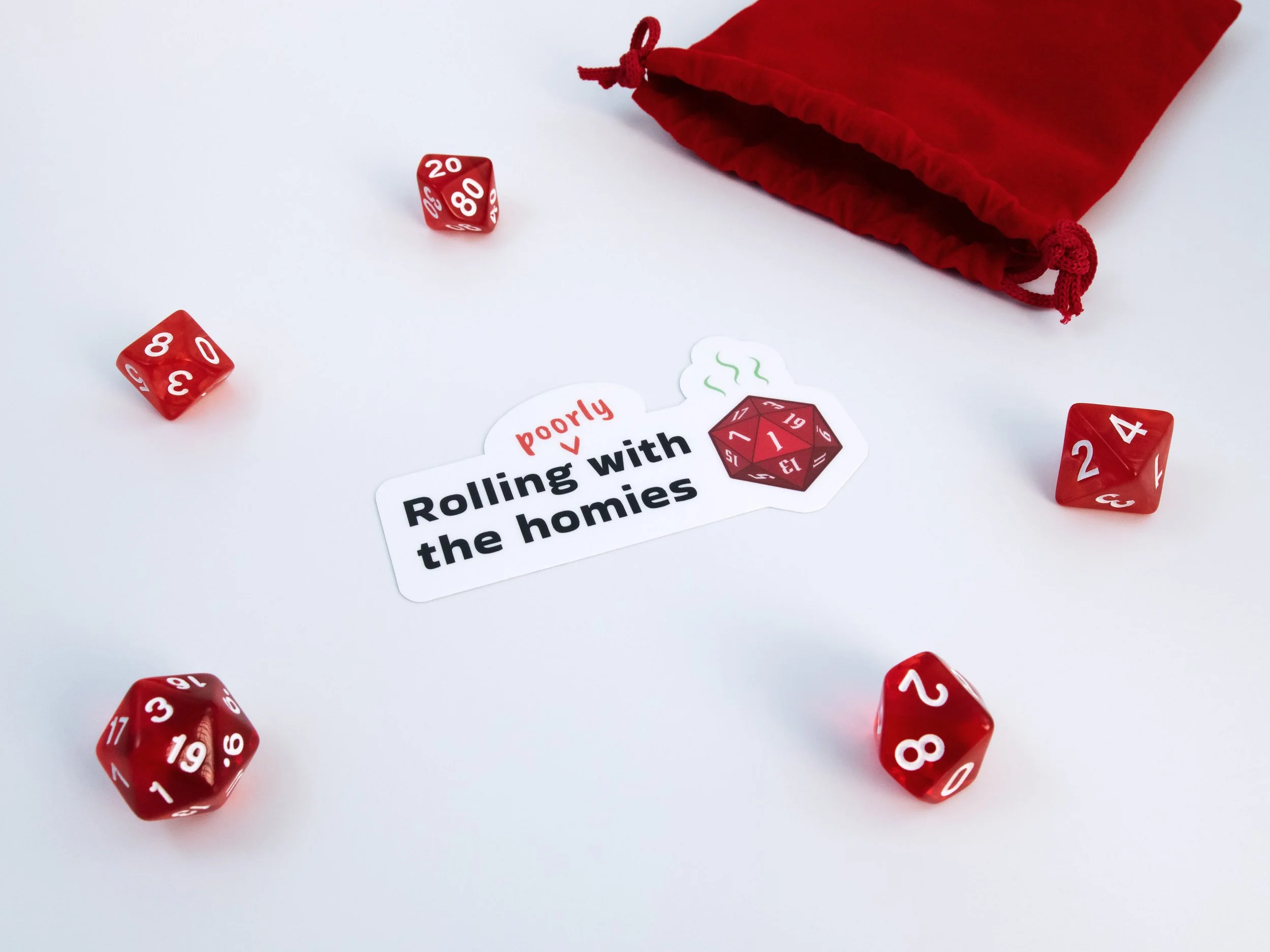 A sticker of a red d20 die with text that says “Rolling poorly with the homies”. The sticker is surrounded by red dice and a red pouch