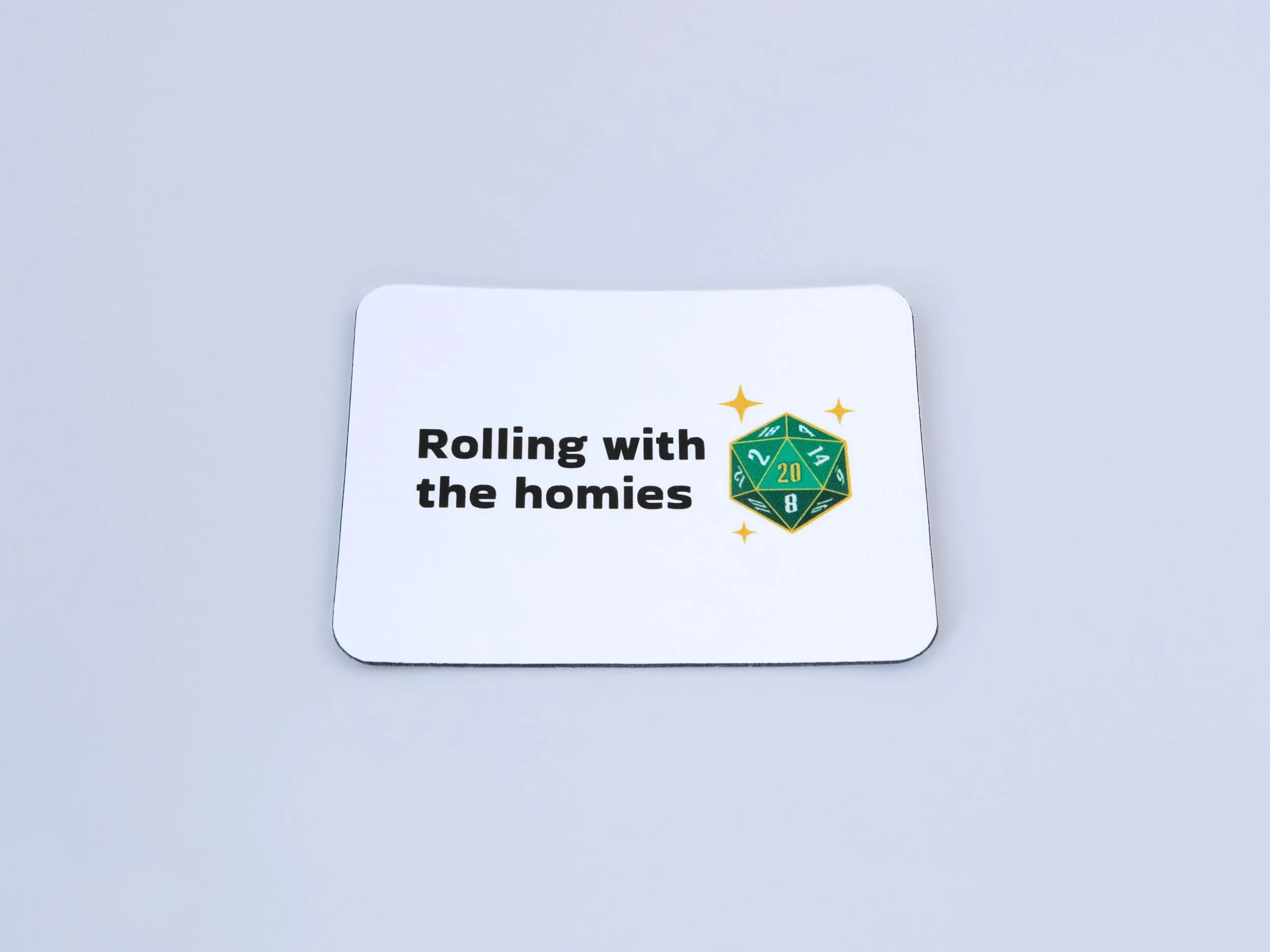 Top view of a magnet. The design is a green d20 die with text that says “Rolling with the homies”