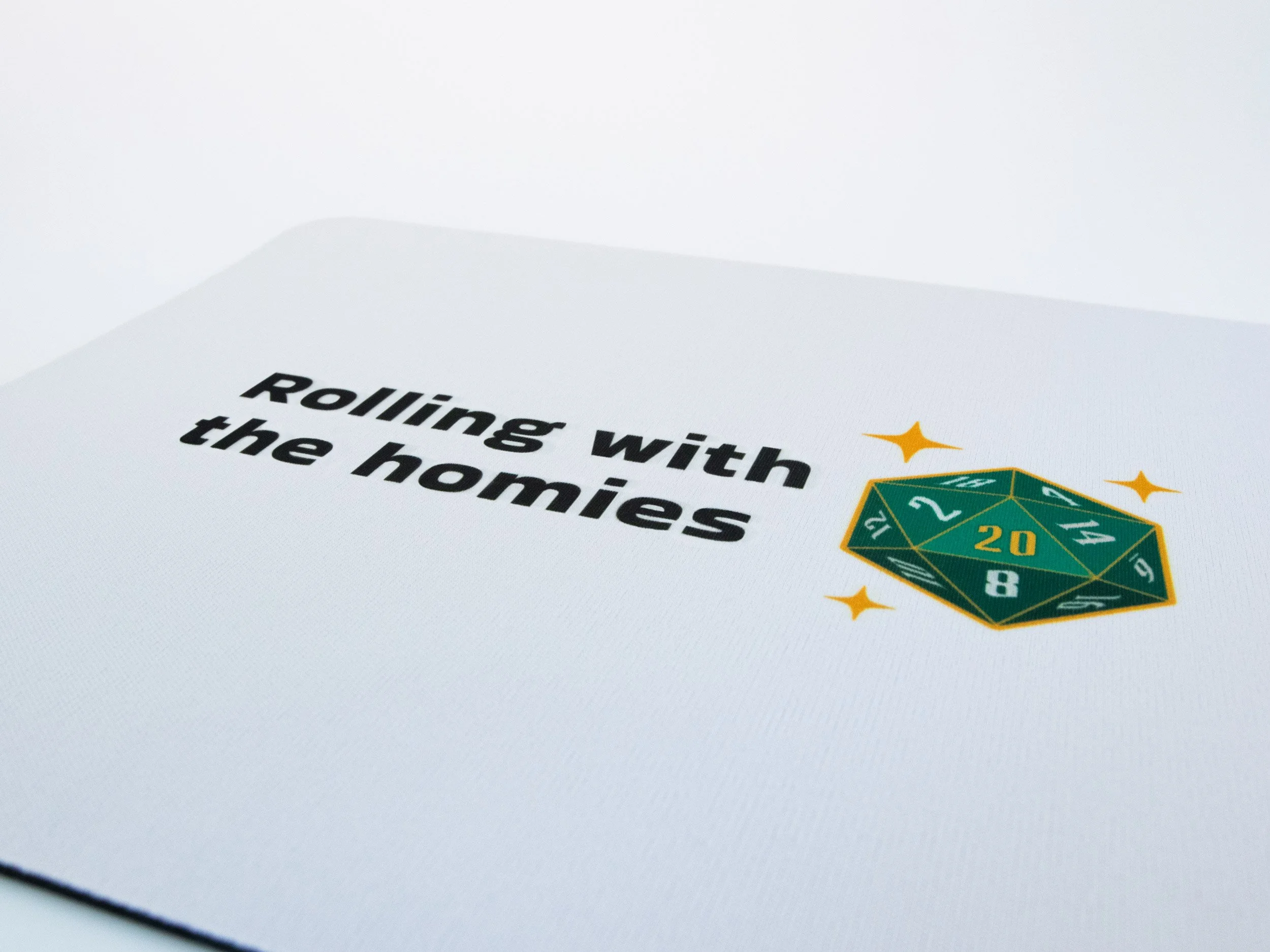 Close up view of a sublimated mousepad. The design says "Rolling with the homies" and features a green d20 die